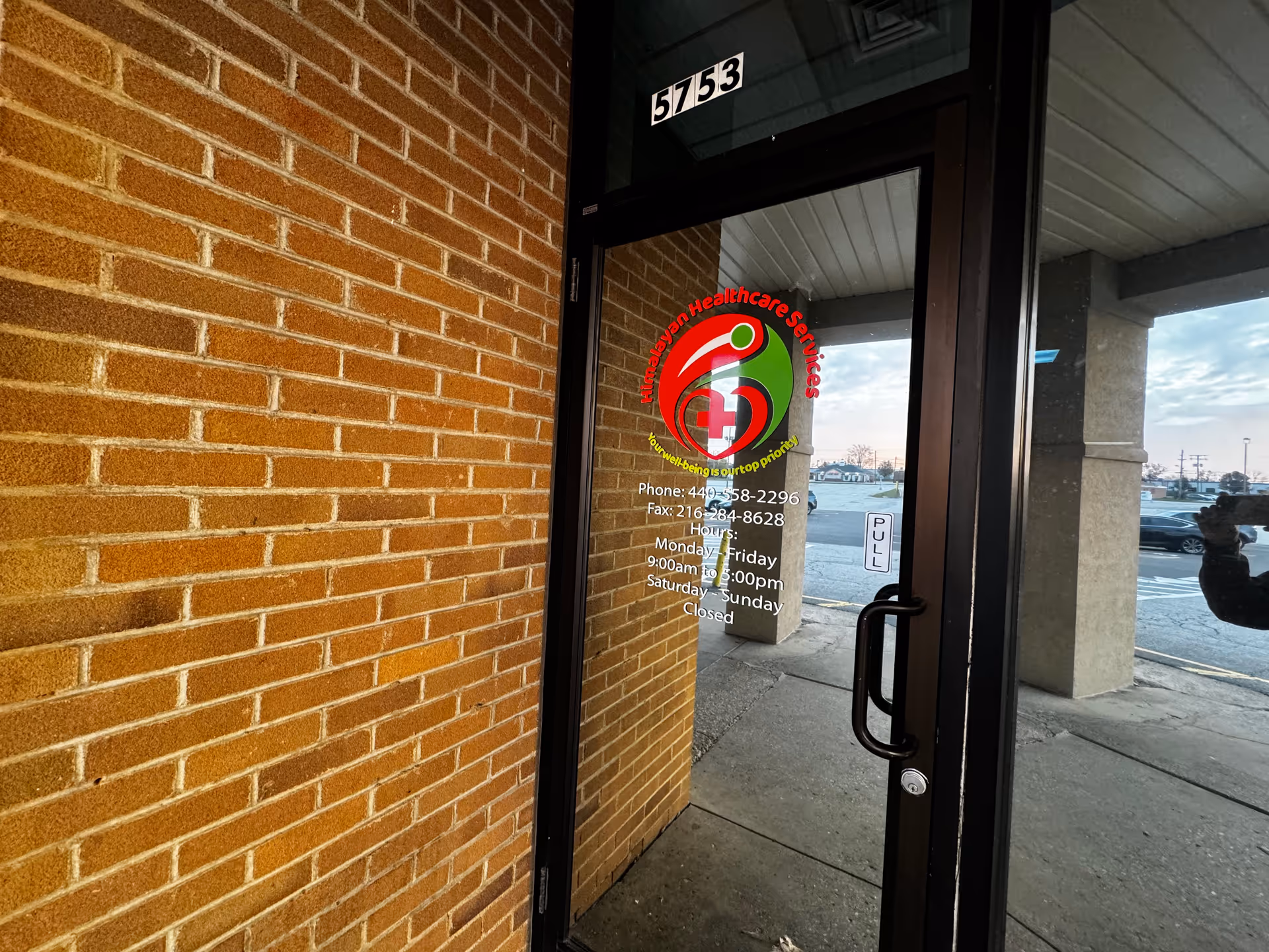 Brick exterior wall and glass door with Himalayan Healthcare Services logo at entrance