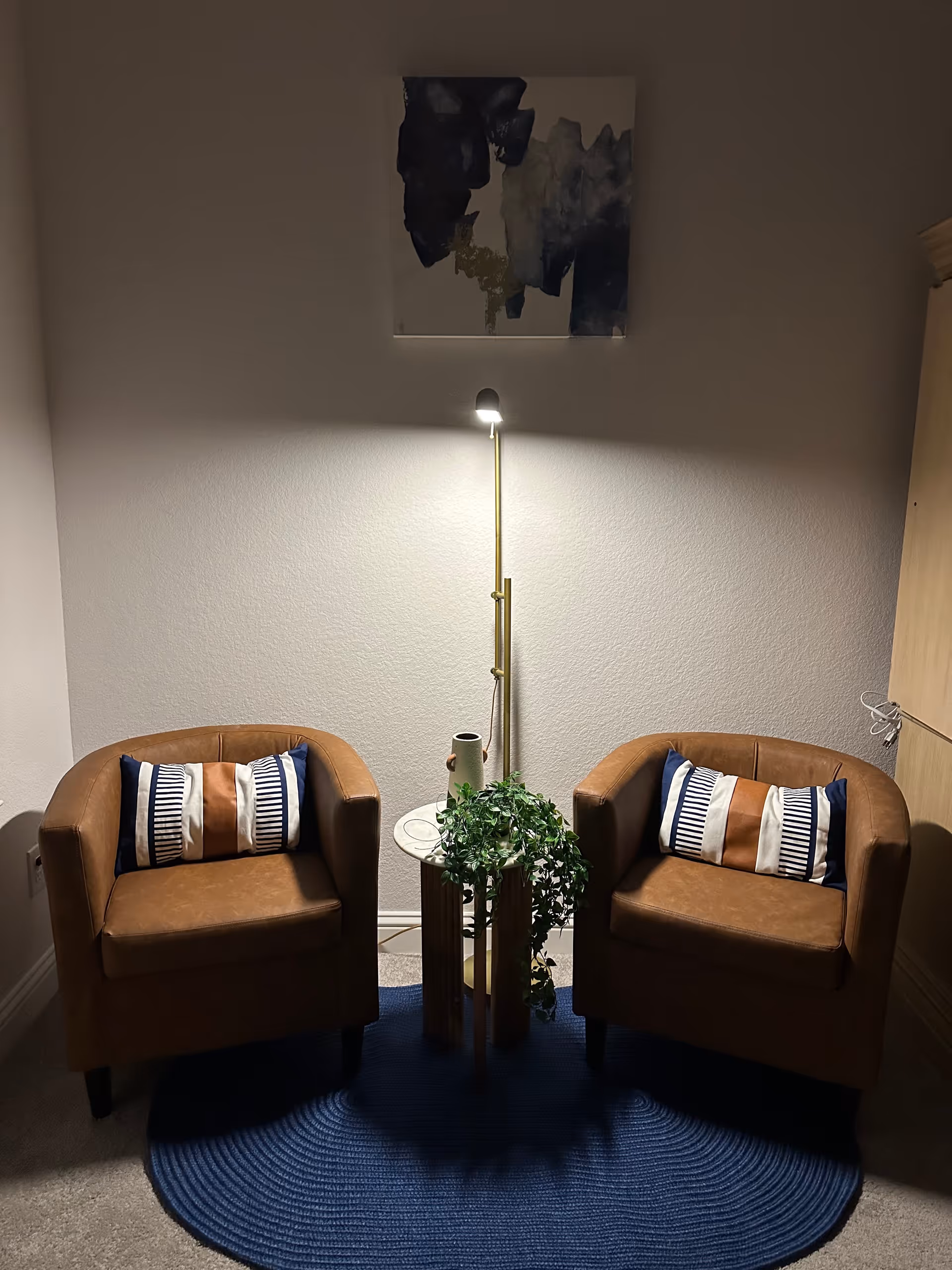 Two brown armchairs with striped cushions flank a small table with a plant.