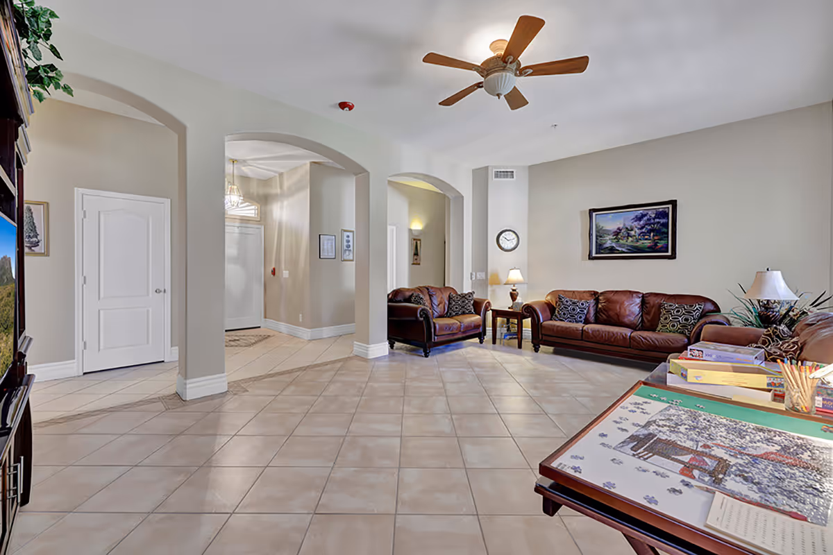 Spacious living room lounge with leather sofas, tiled floor, and arched entryways.