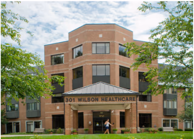 Brick three-story building with entrance canopy and surrounding greenery at Wilson Healthcare Center.