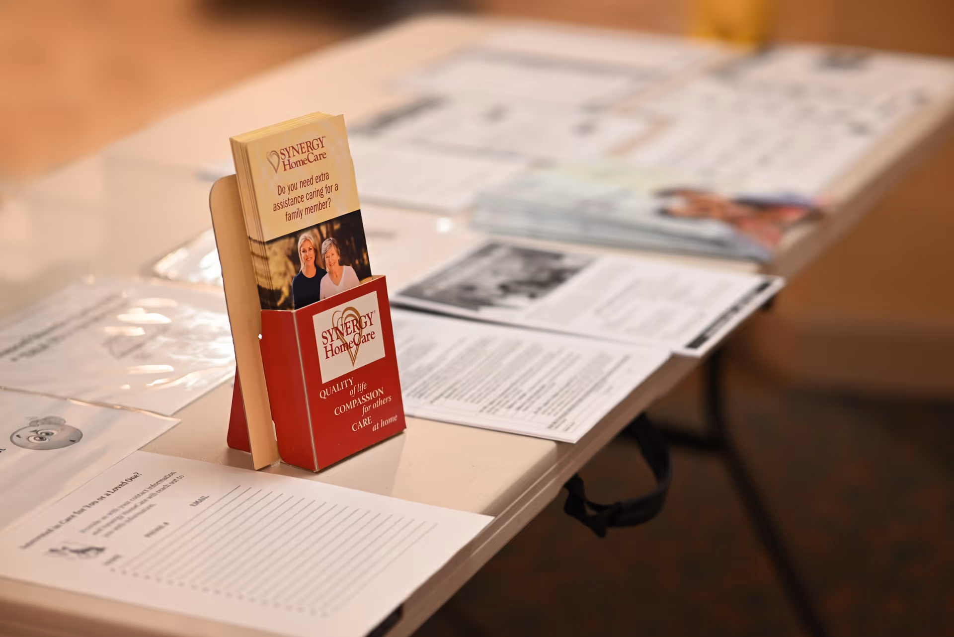 Table with brochures and a SYNERGY HomeCare Bel Air promotional display.