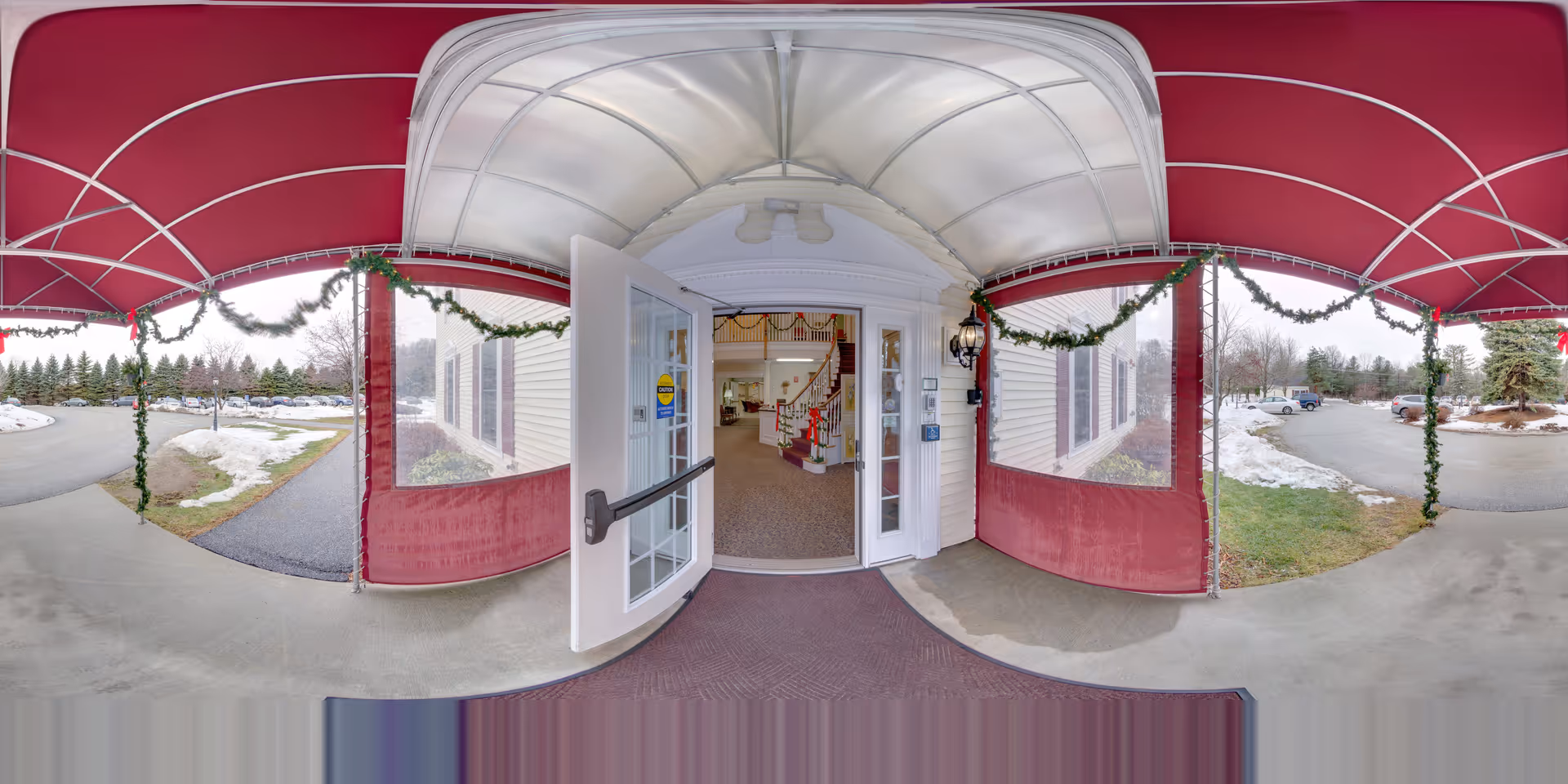 Red canopy entrance to Schooner Estates Residential Care with garlands and open glass doors.