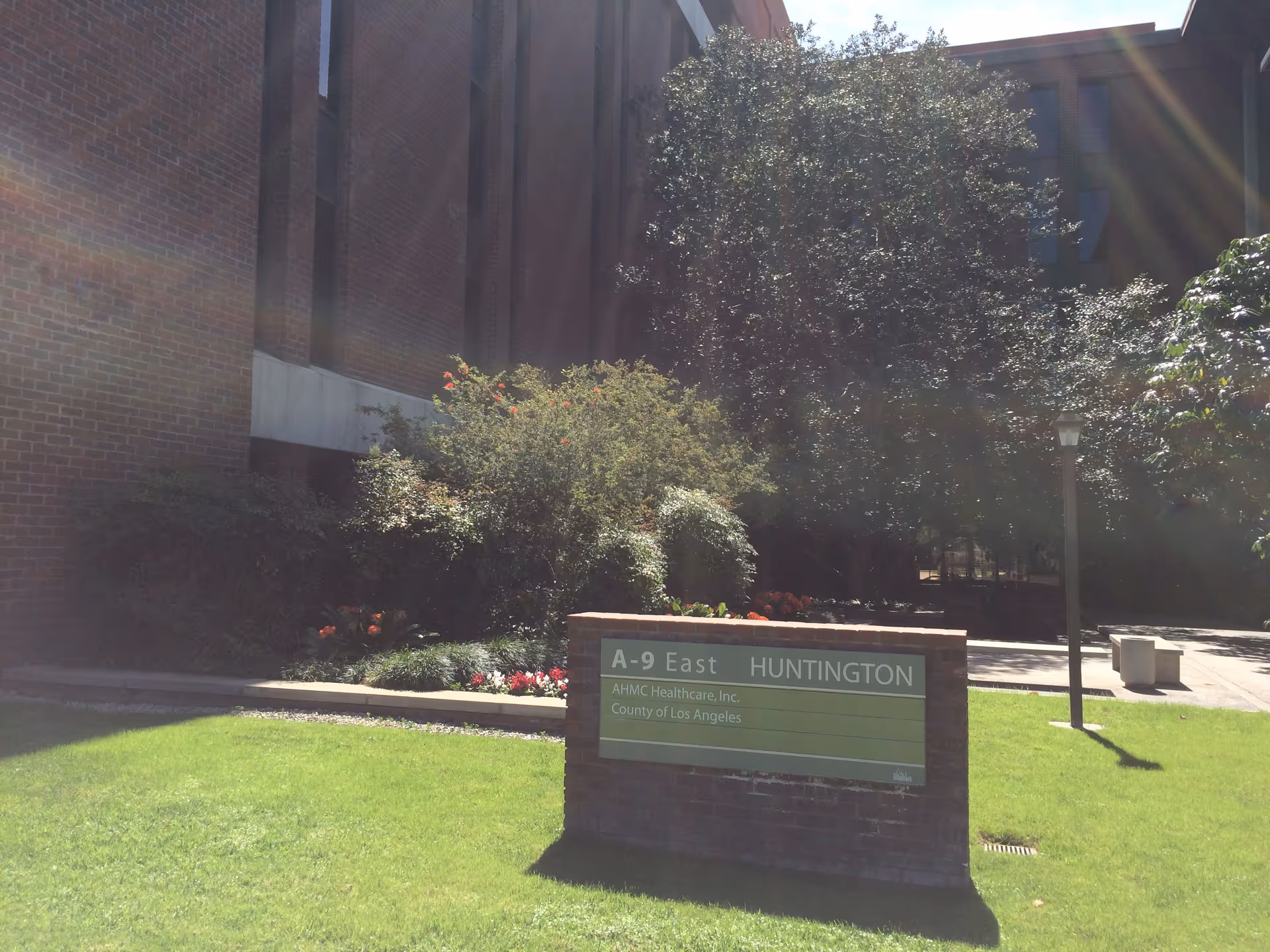 Brick building with a green lawn, shrubs, and a sign reading AHMC Huntington.