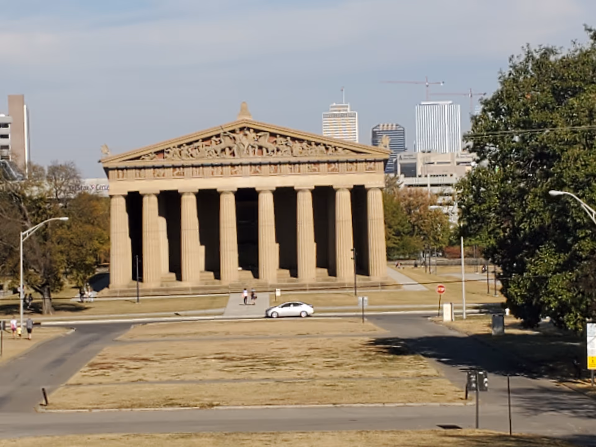 Neoclassical temple with tall columns in a park with city skyline beyond