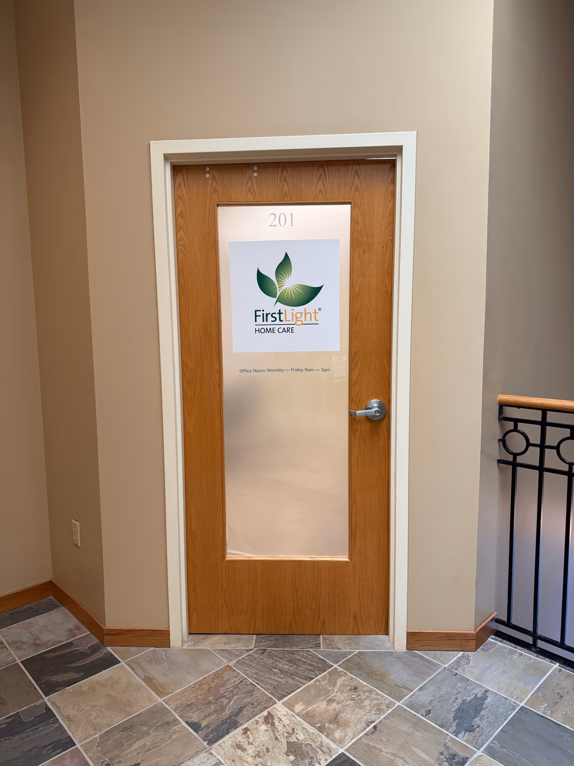 Interior hallway with a wooden door labeled 201 displaying a FirstLight Home Care sign.