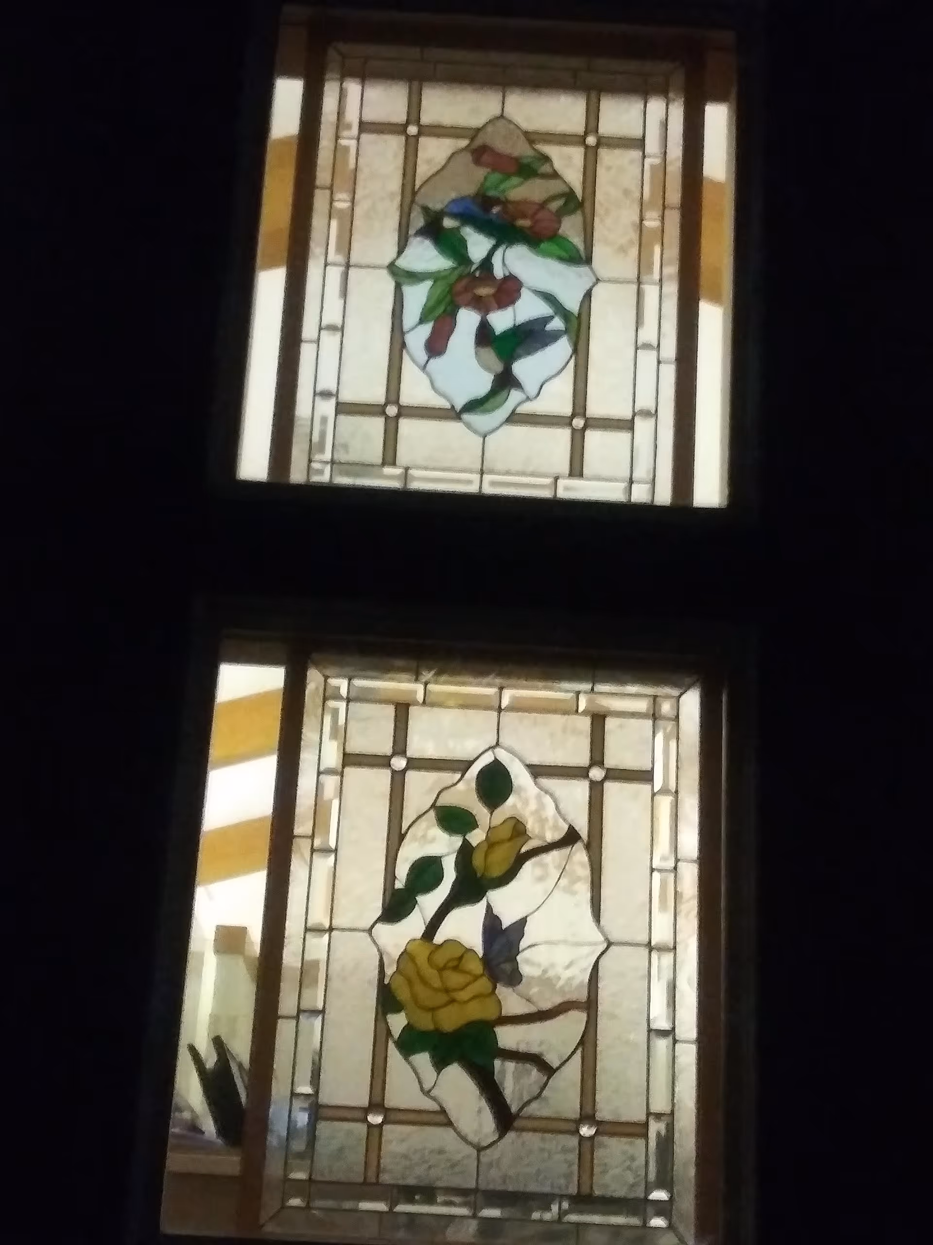 Dim interior with two stacked stained-glass panels depicting flowers.