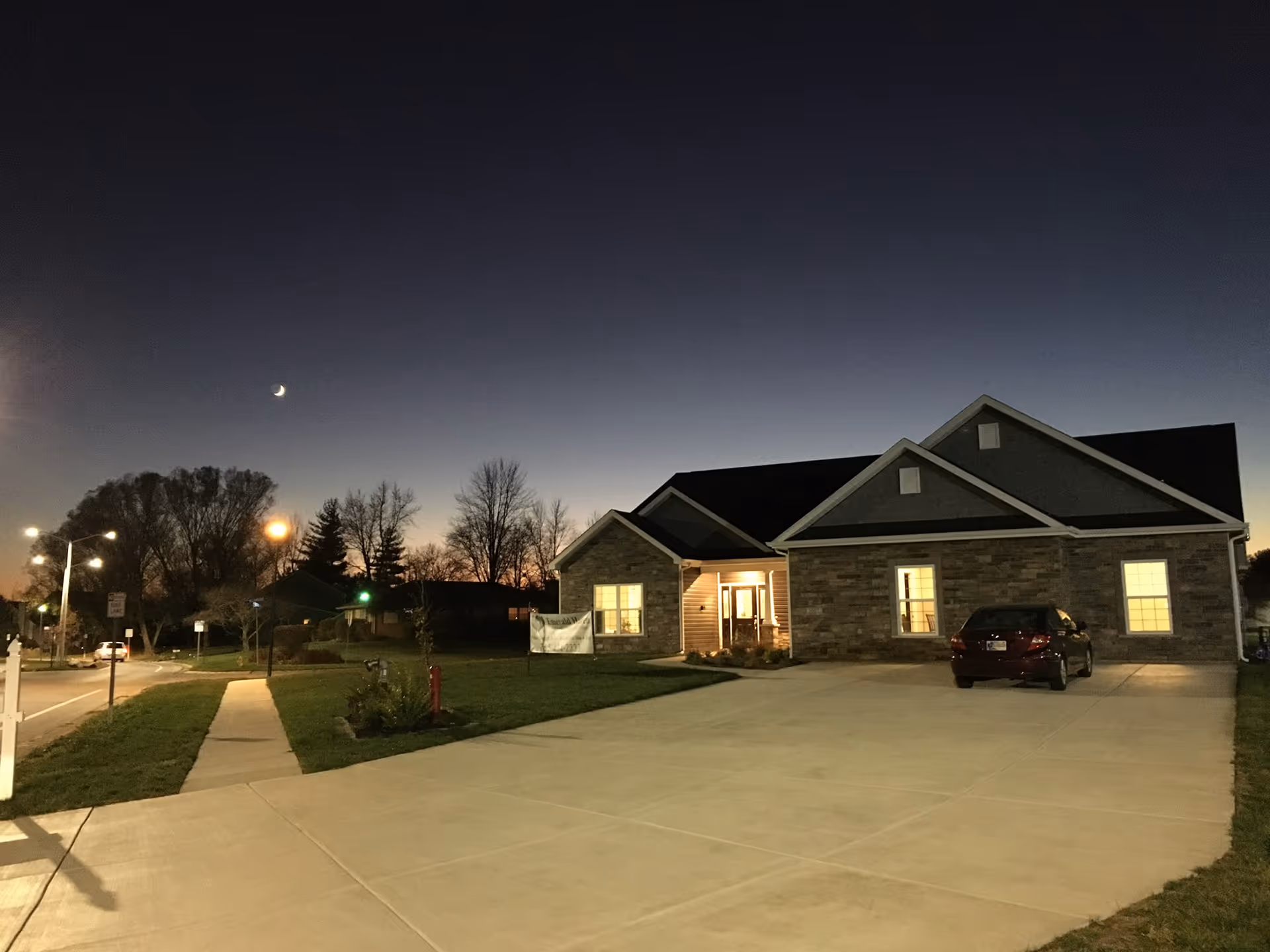 Evening exterior of Emerald Haven senior living facility with a driveway and parked car.