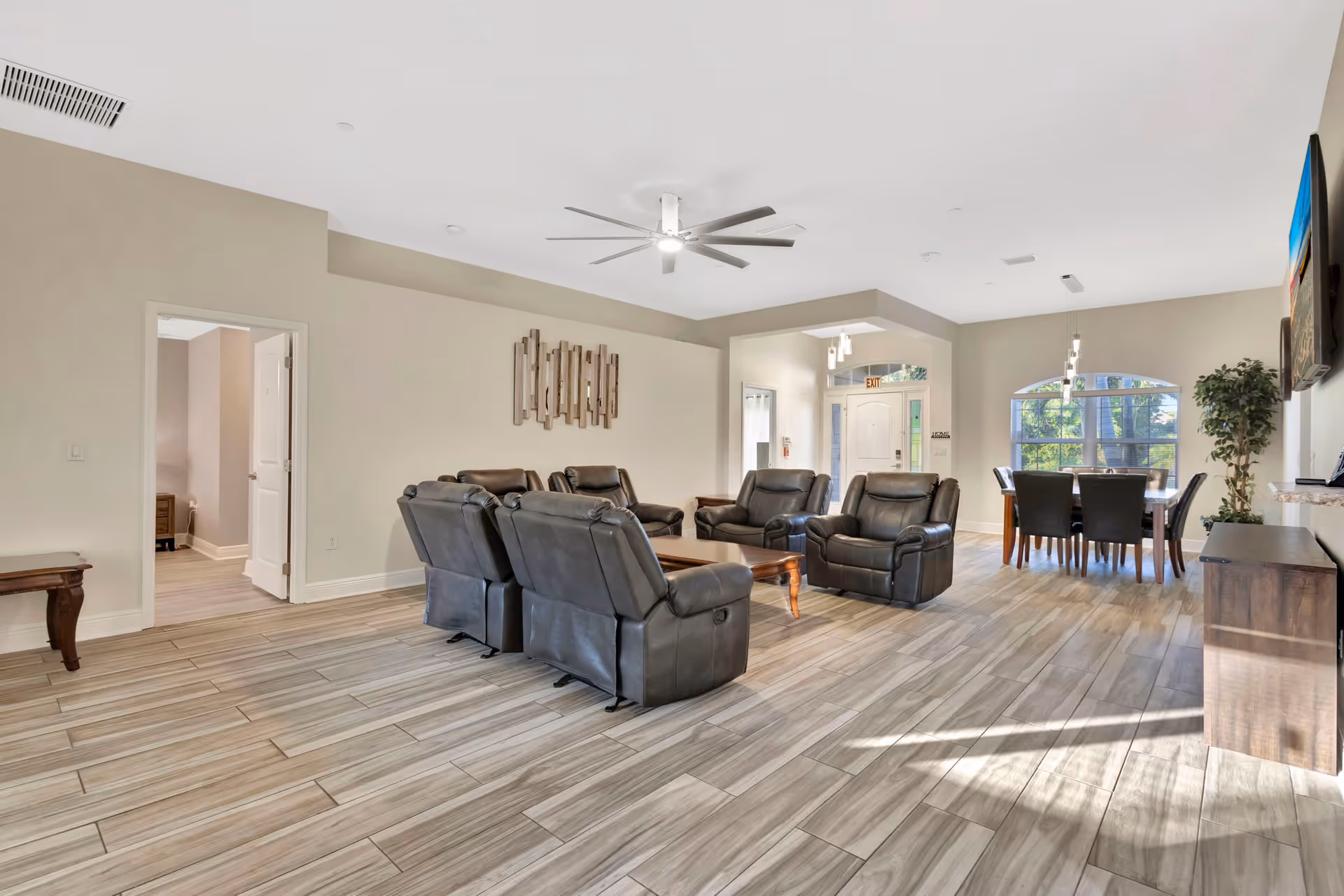 Spacious lounge area with leather recliners, a dining table, and a TV mounted on the wall.