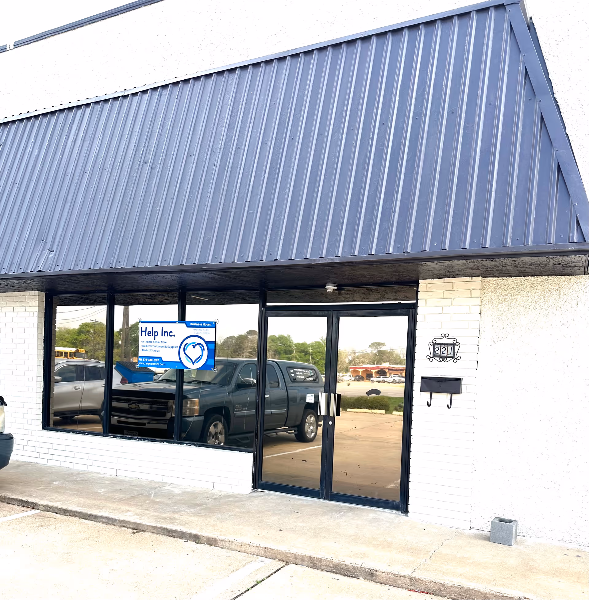 Exterior view of a building front with glass doors and a Help Inc. sign
