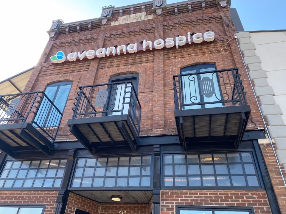 Brick storefront with Aveanna Hospice signage and decorative balconies.