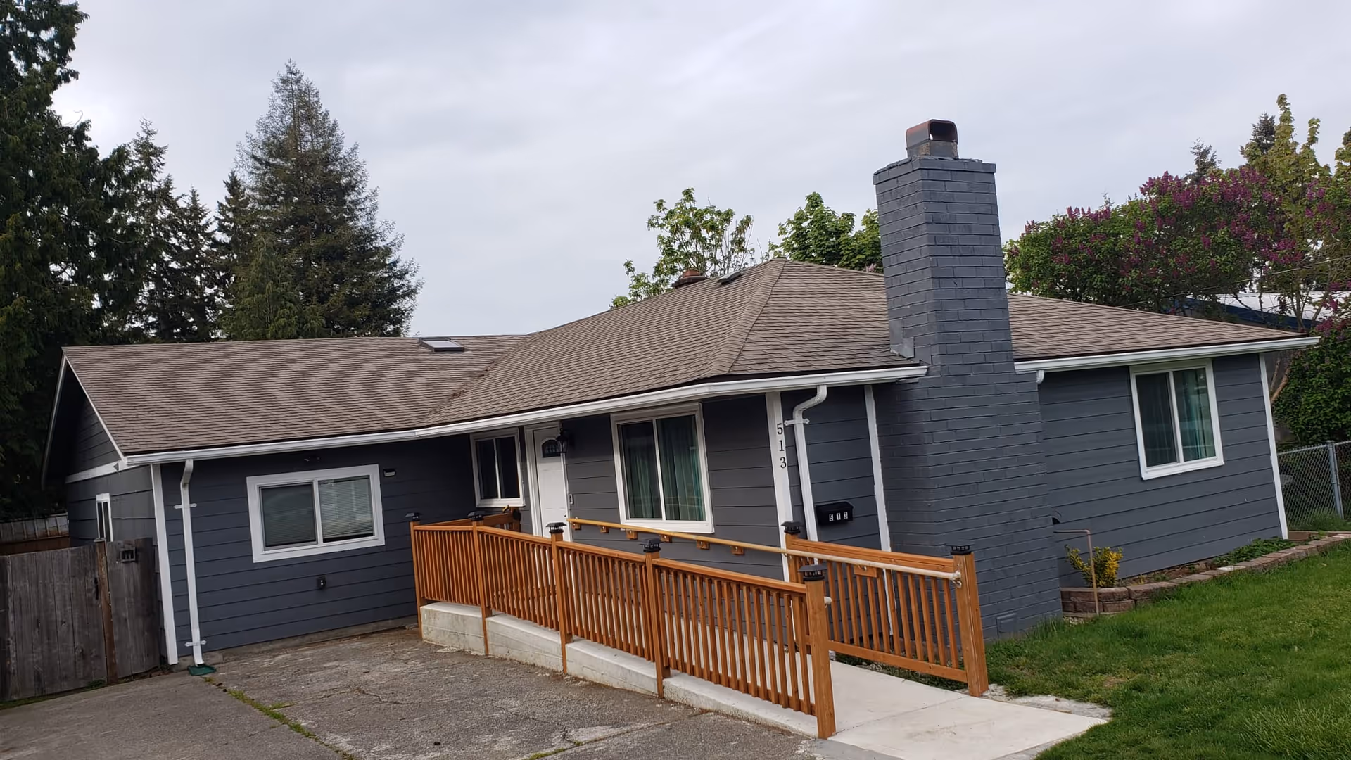 Exterior view of a single-story blue-gray senior living home with a wooden ramp at the front