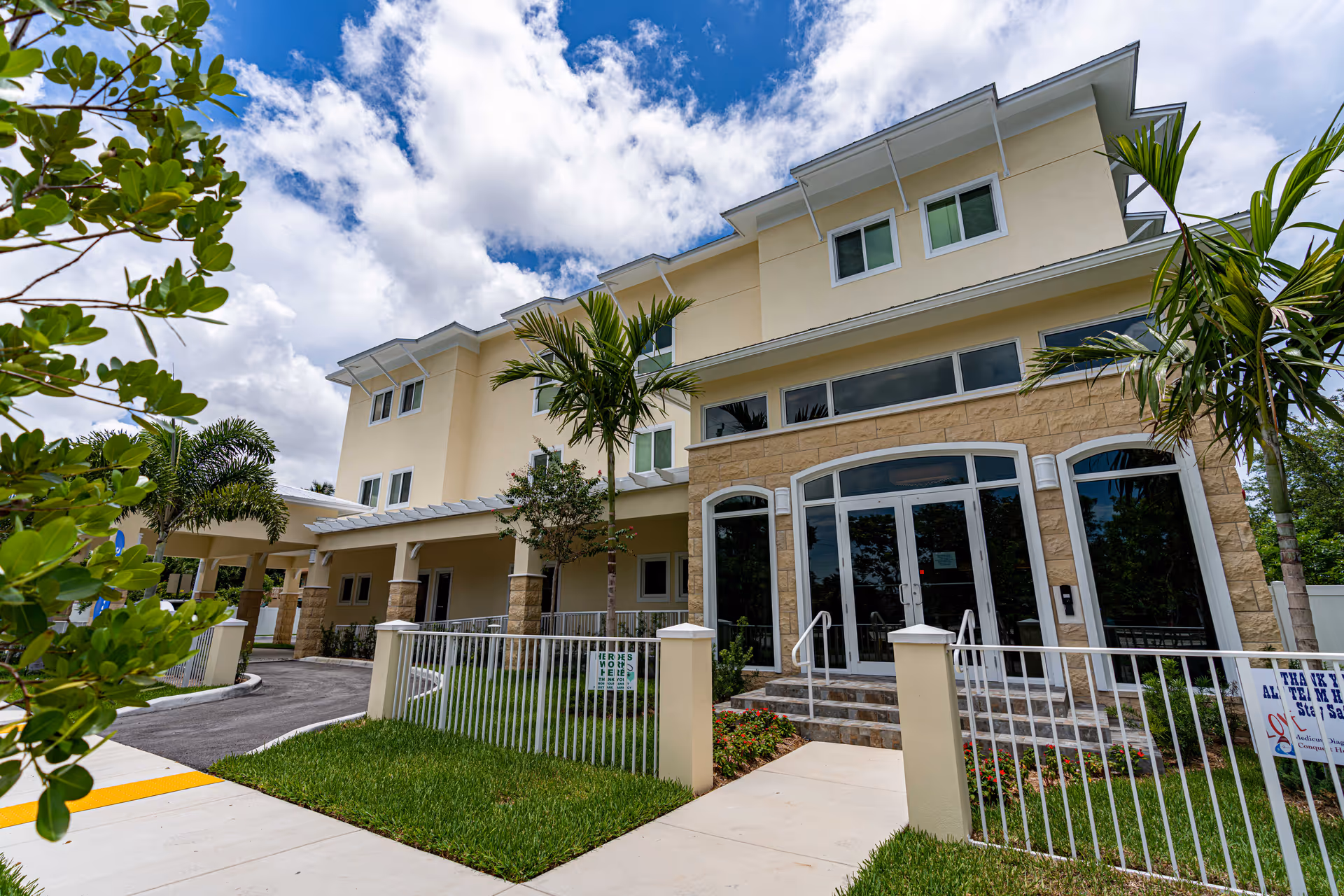 MiCasa Senior Living building exterior with glass entrance and palm trees.