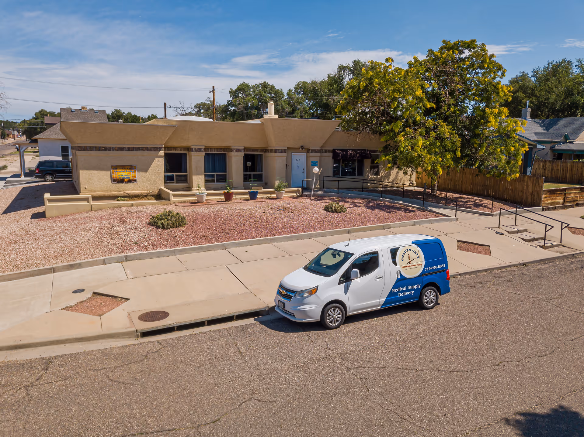 Single-story beige senior living facility with a white and blue delivery van parked outside.