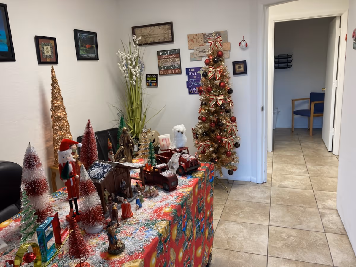 Holiday decorations and small Christmas trees arranged on a table in a decorated hallway interior.