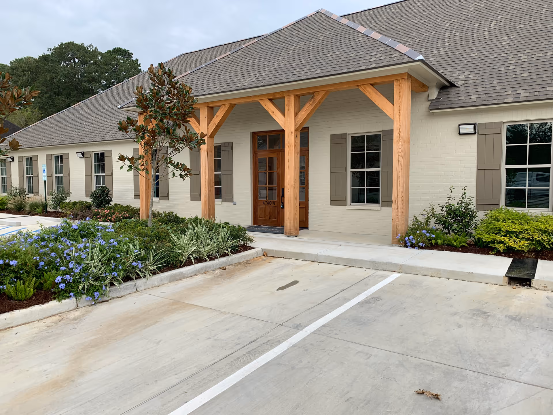 Exterior view of a senior living facility entrance with wooden porch and landscaped yard.