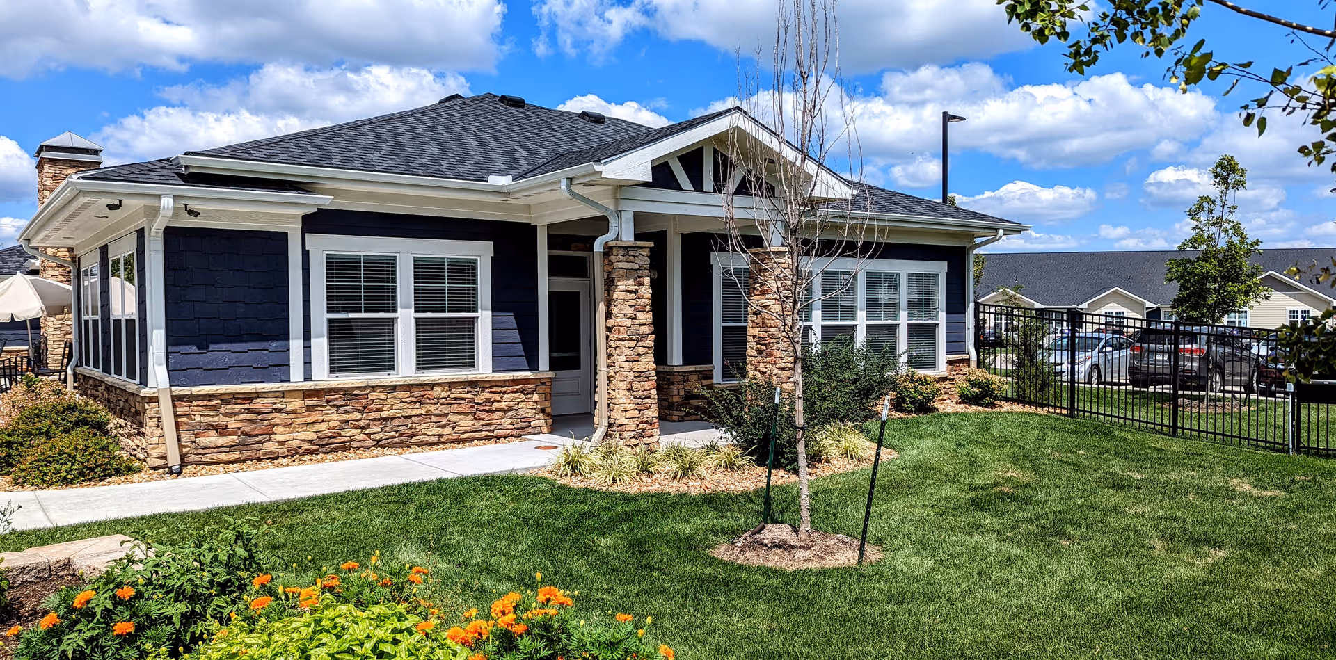 Front of a single-story building with blue siding, stone accents, and a manicured lawn.