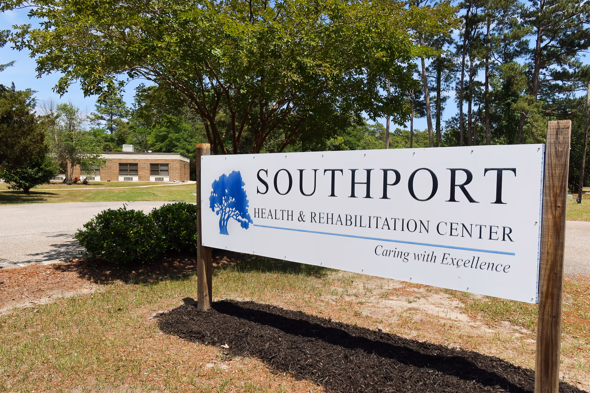Large sign reads Southport Health & Rehabilitation Center with trees and a building in background.