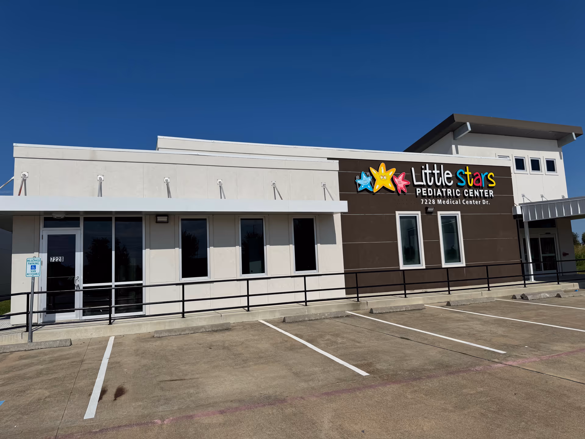 Modern single-story building with a colorful Little Stars Pediatric Center sign and parking lot