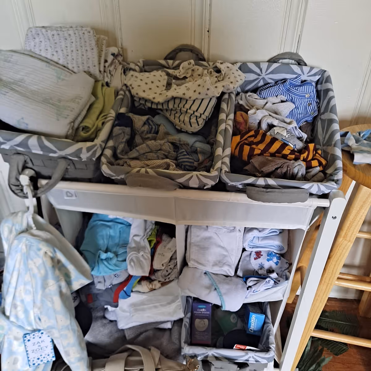 Two laundry baskets on a rolling cart overflow with folded clothes indoors.