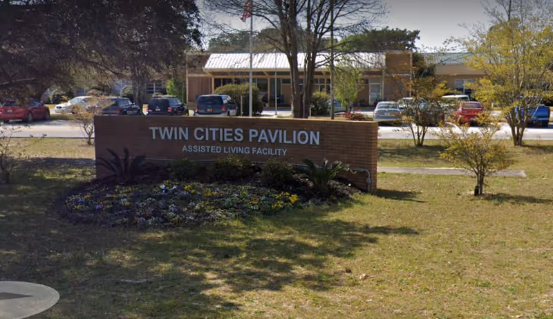 Exterior view of Twin Cities Pavilion sign with building and parking lot behind.