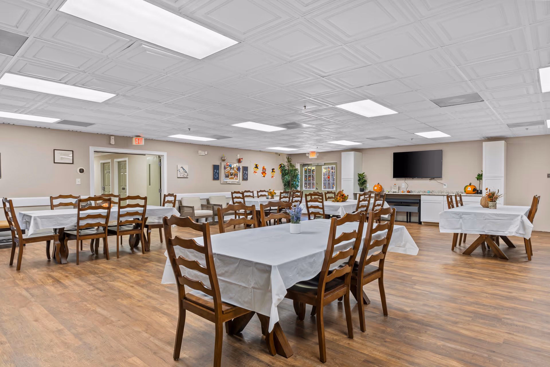 A spacious dining hall with white tablecloths and wooden chairs.