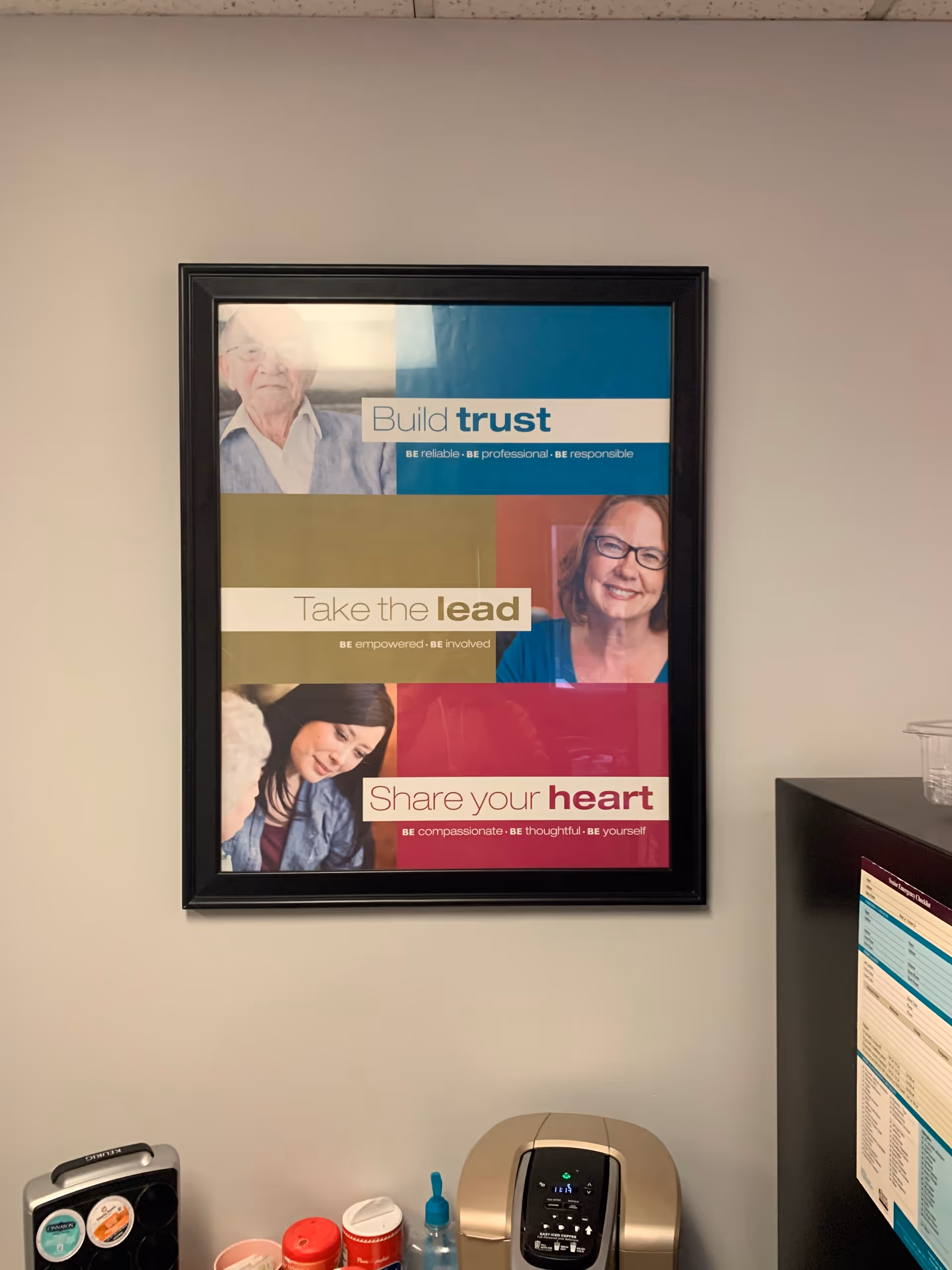 Framed motivational poster on wall above a coffee station in a senior care facility.