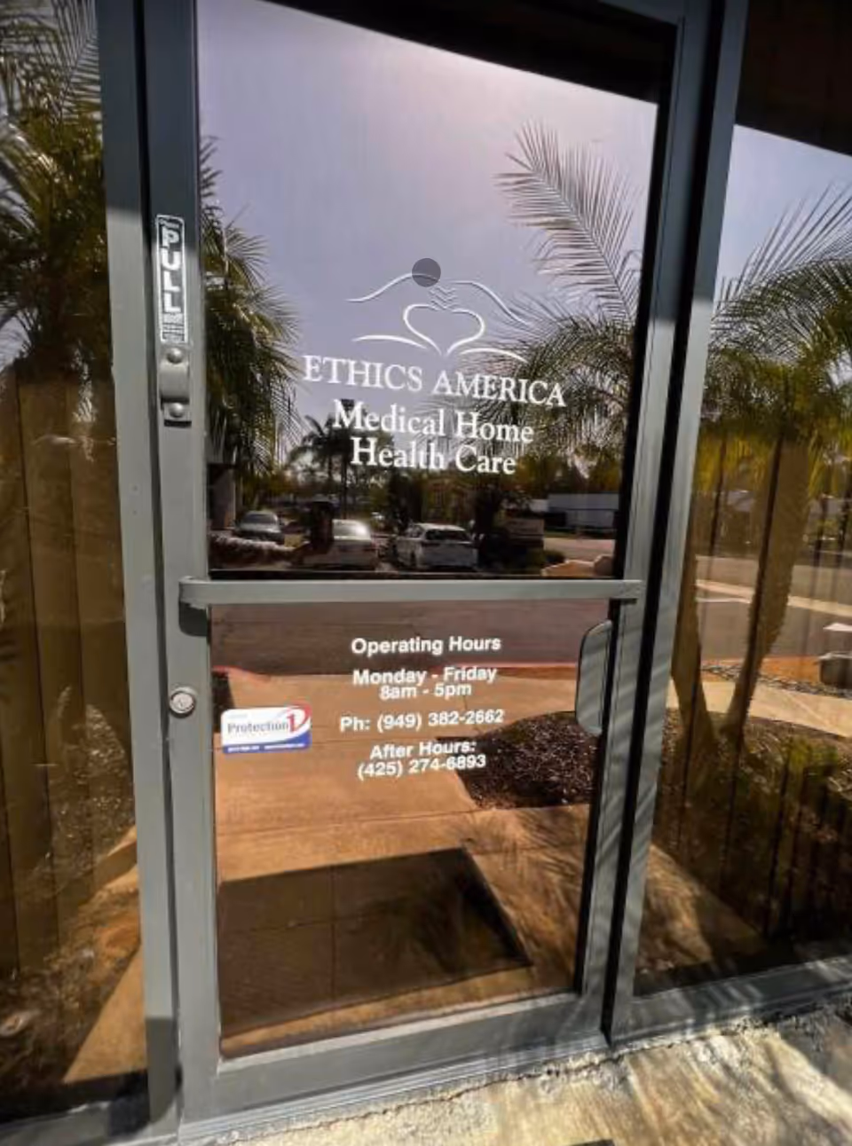 Glass entrance to Ethics America Medical Home Health Care with palm tree reflections.