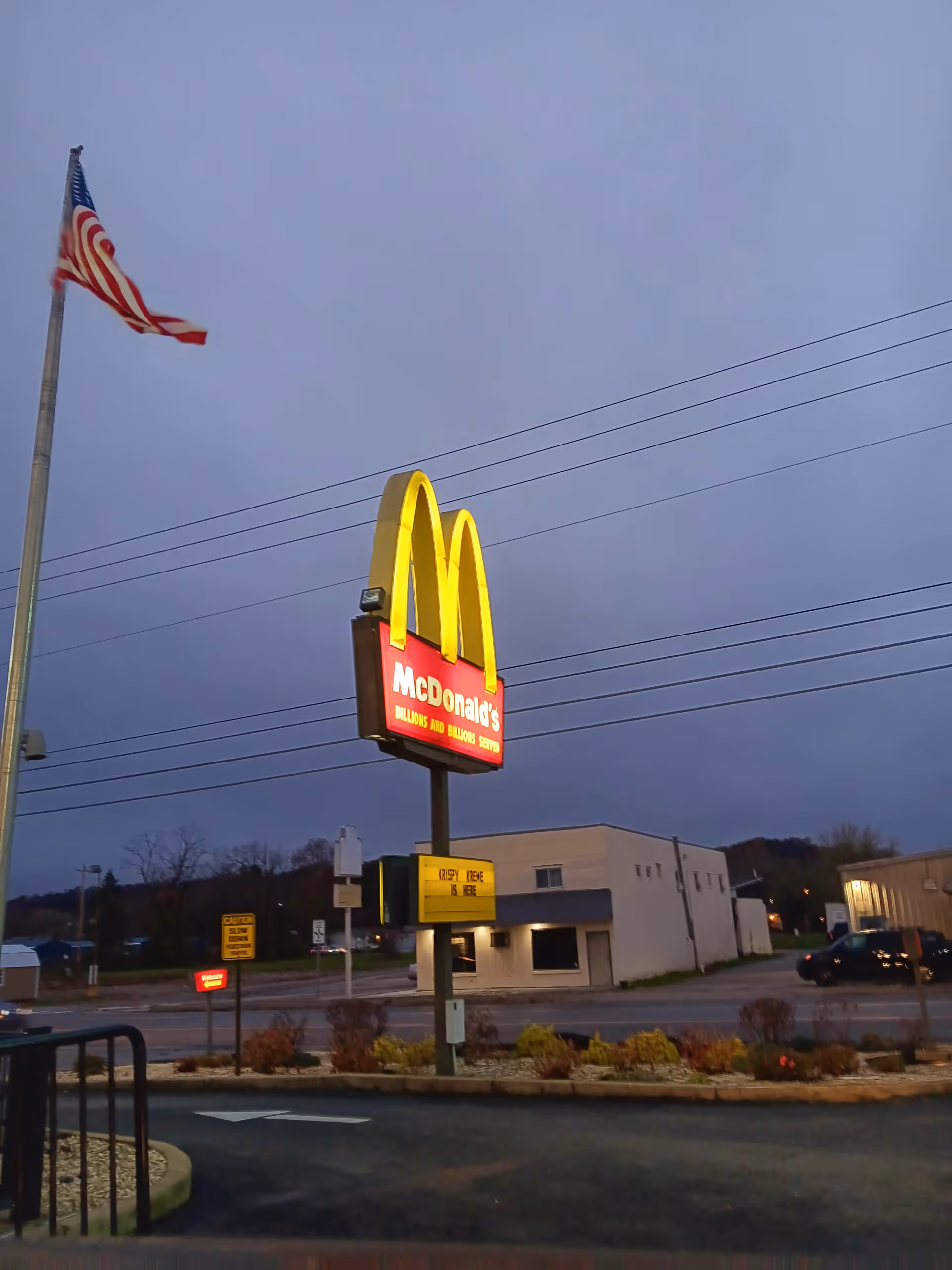 McDonald's golden arches sign beside a small building at dusk.