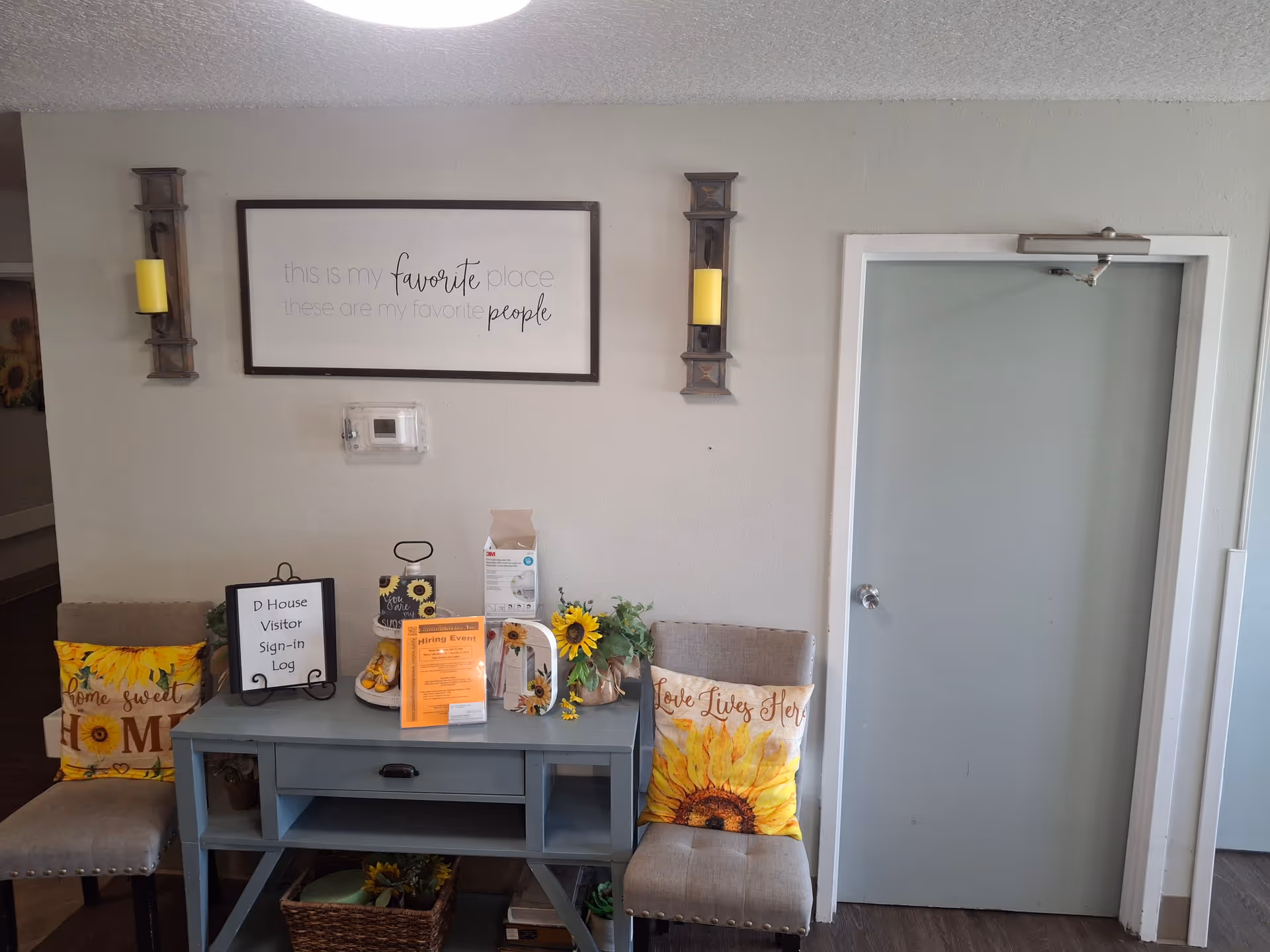 Indoor entry area with a blue console table, sunflower pillows, and wall sign