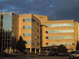 SeniCare Plus building front with glass windows, brick exterior, and parked cars.