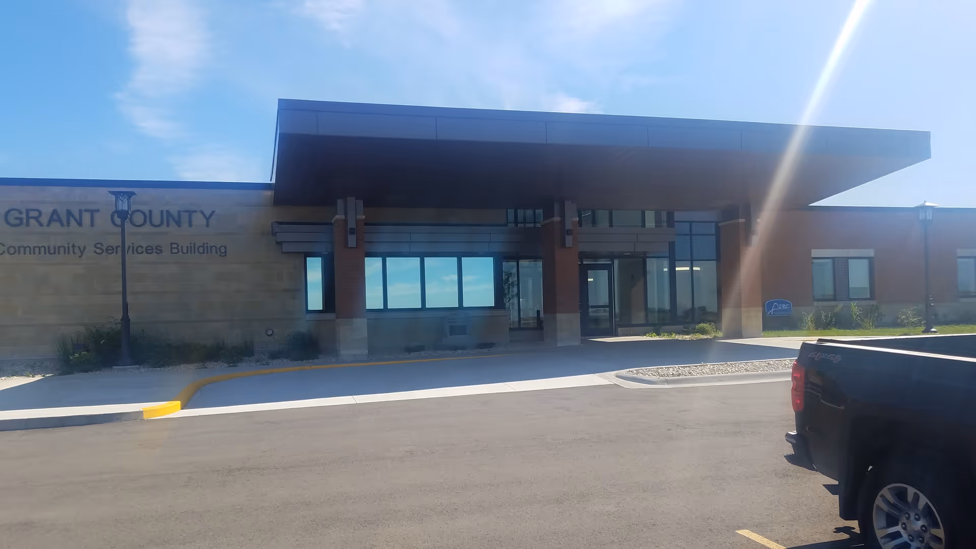 Exterior view of a modern community services building with a glass entrance and parked pickup.