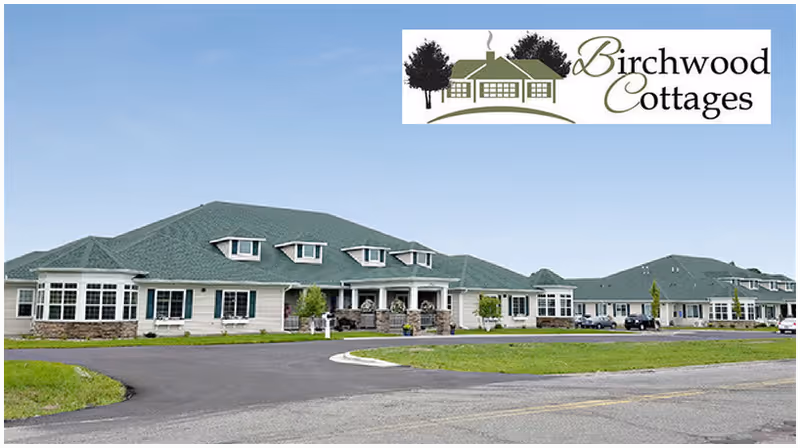 Wide exterior view of Birchwood Cottages senior living facility with green roofs and signage.