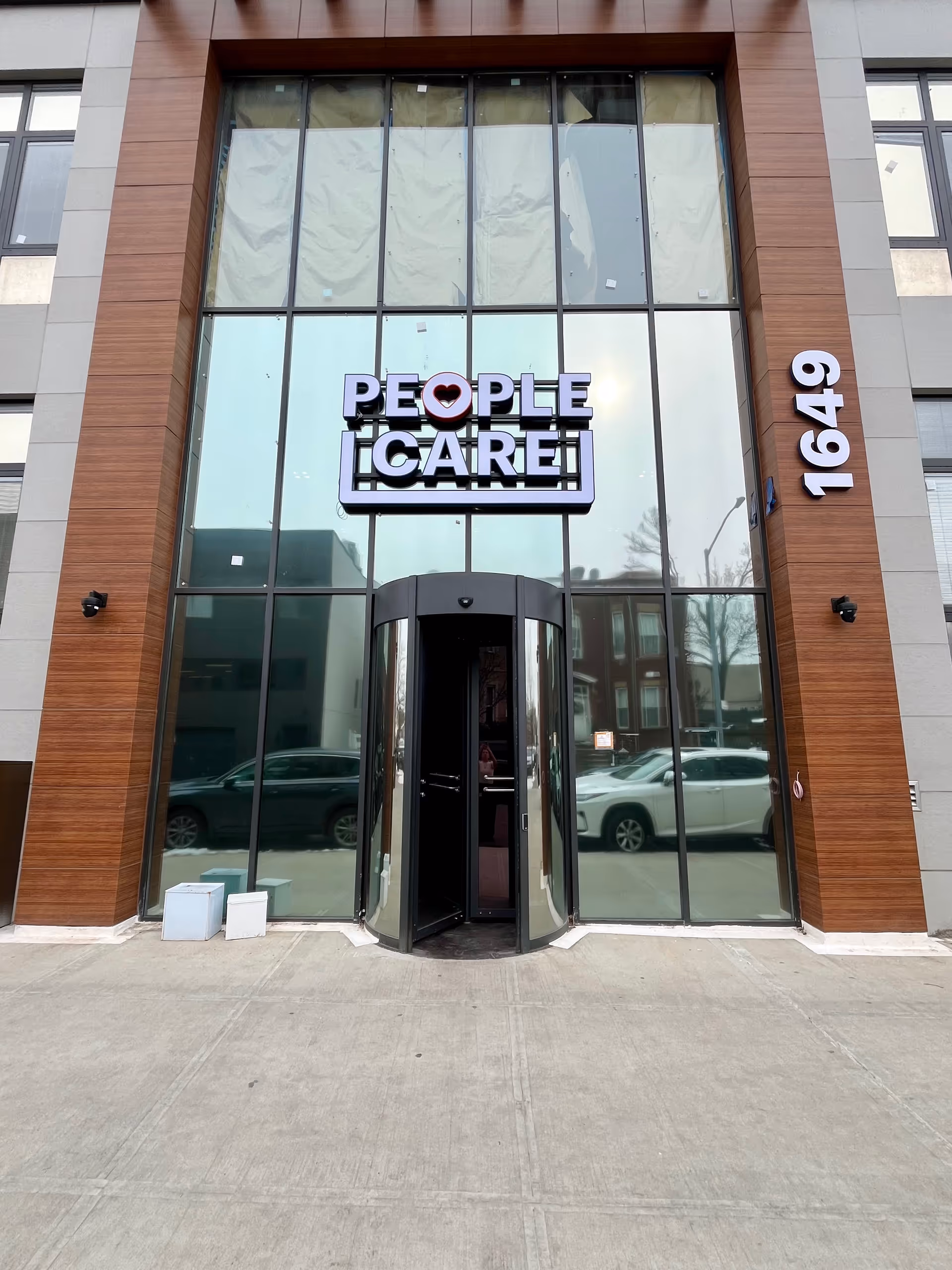 Modern glass-front building exterior with large 'People Care' sign and entrance.