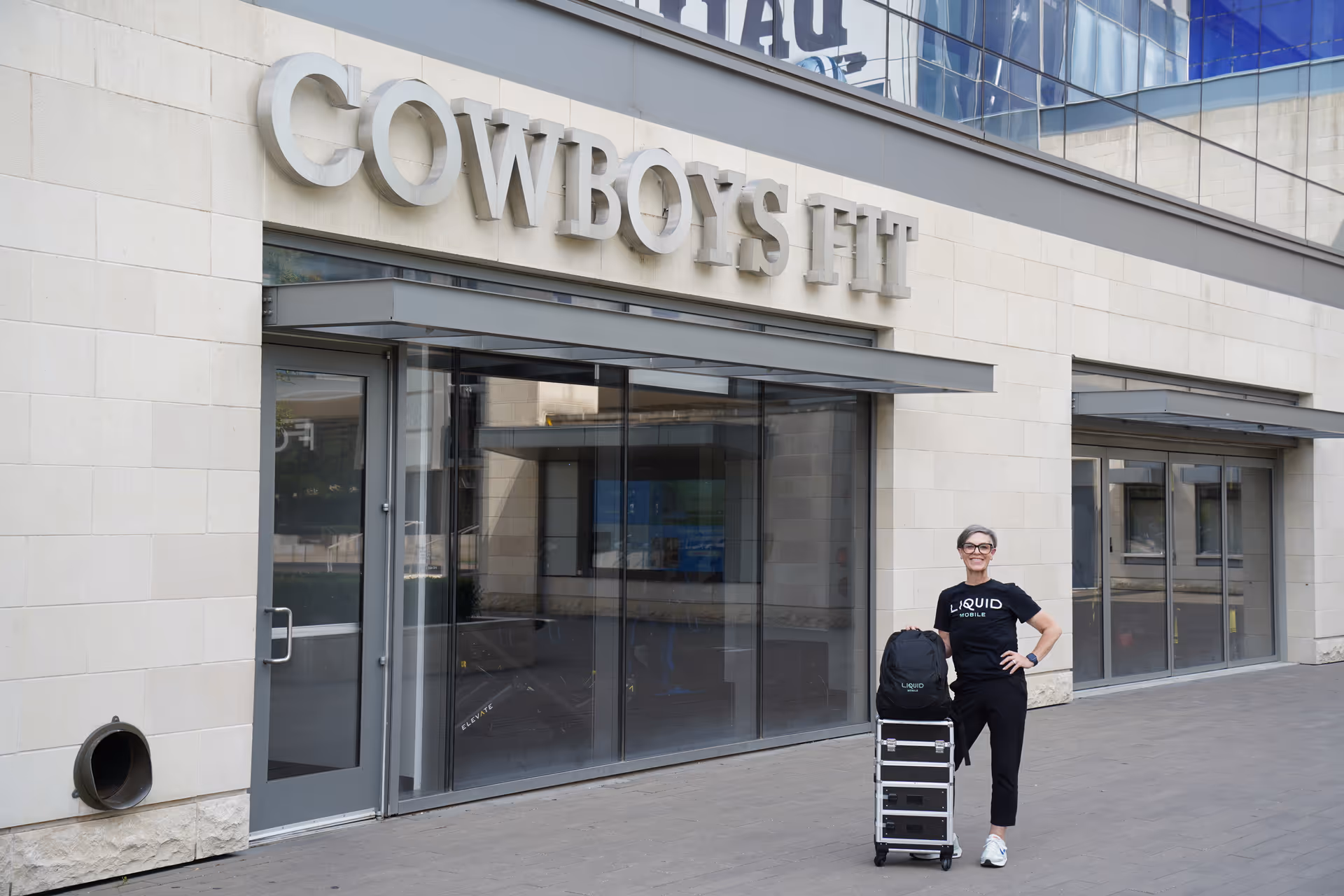 Liquid Mobile IV staff outside Cowboys Fit gym with rolling cart.
