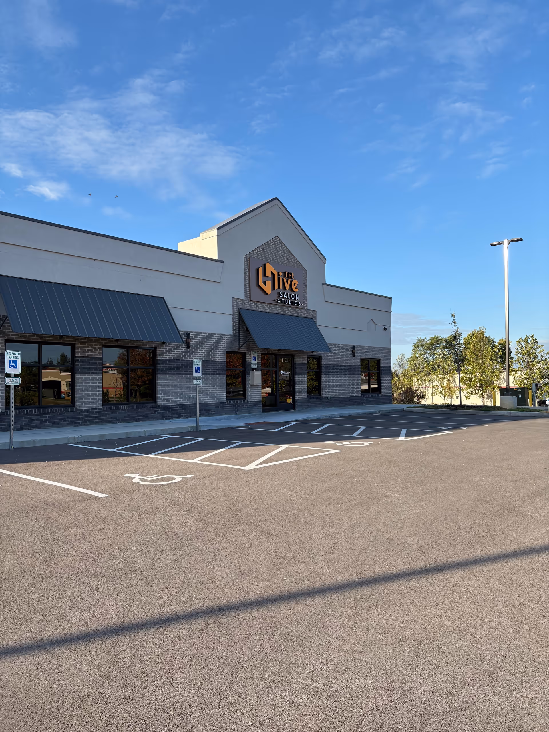 Exterior view of a modern storefront with handicap parking and a clear blue sky.