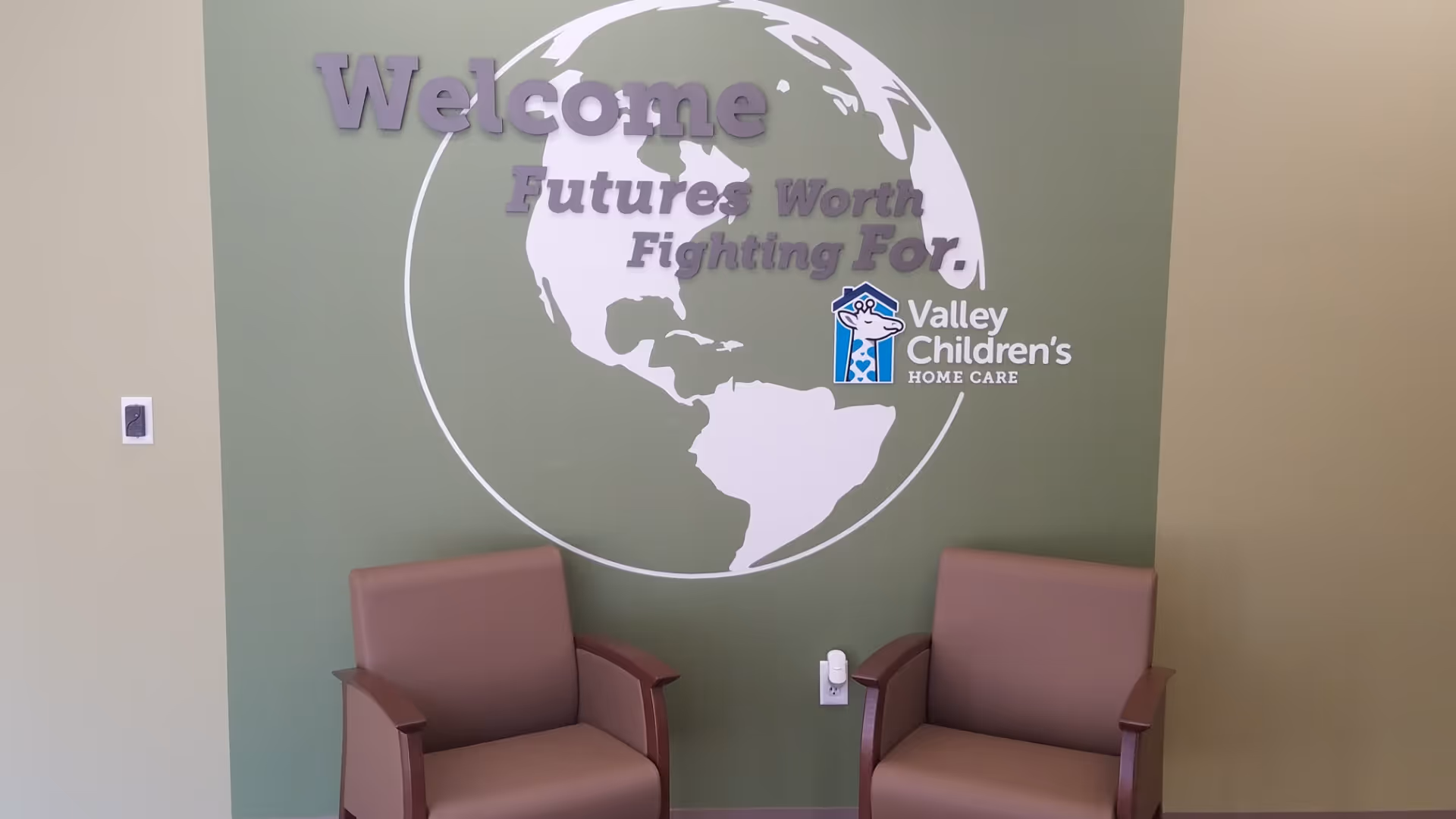 Lobby area with two brown chairs and a green wall mural reading Valley Children's Home Care.