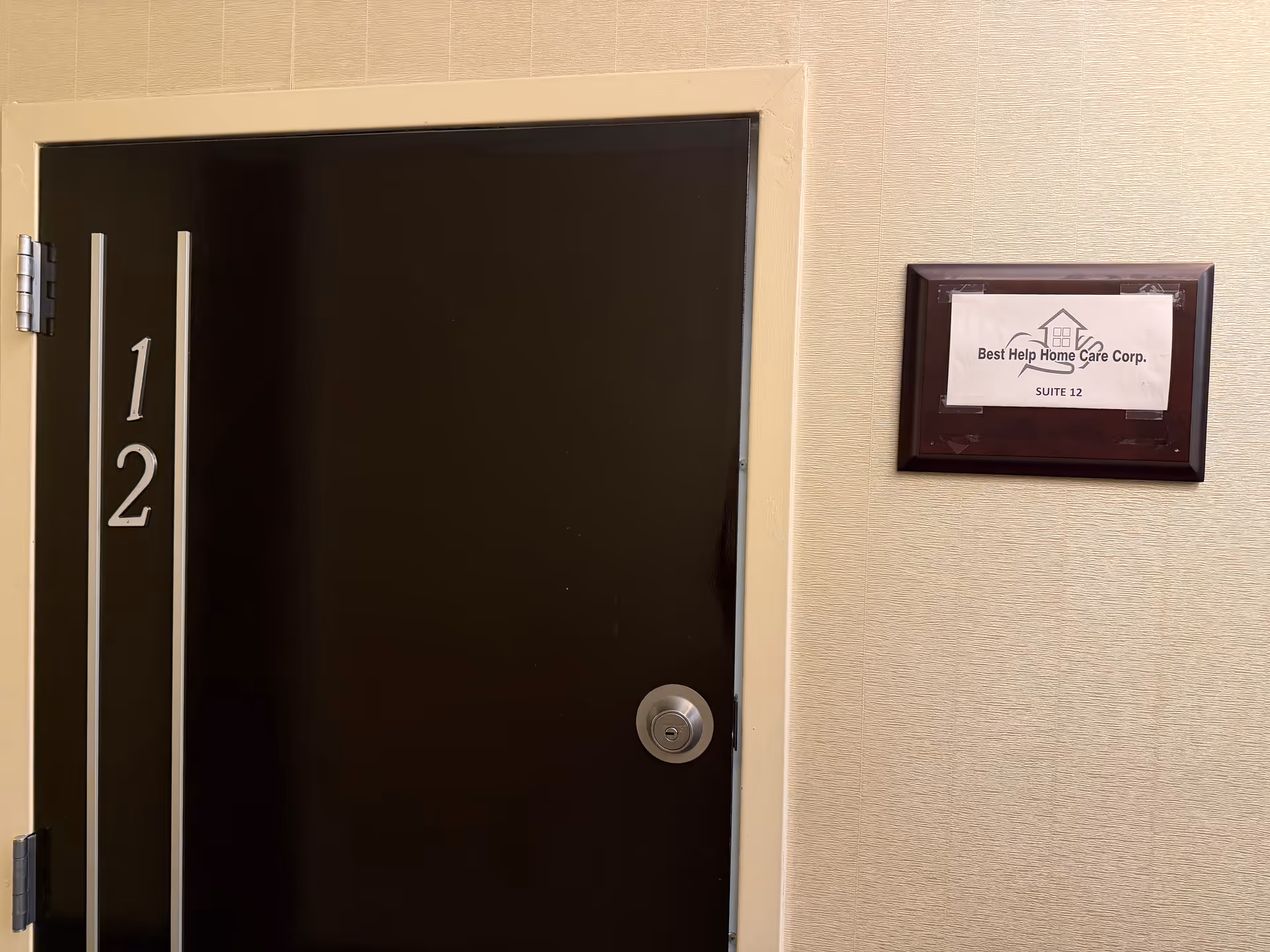 Interior hallway with a dark door and a suite plaque reading Best Help Home Care Corp.