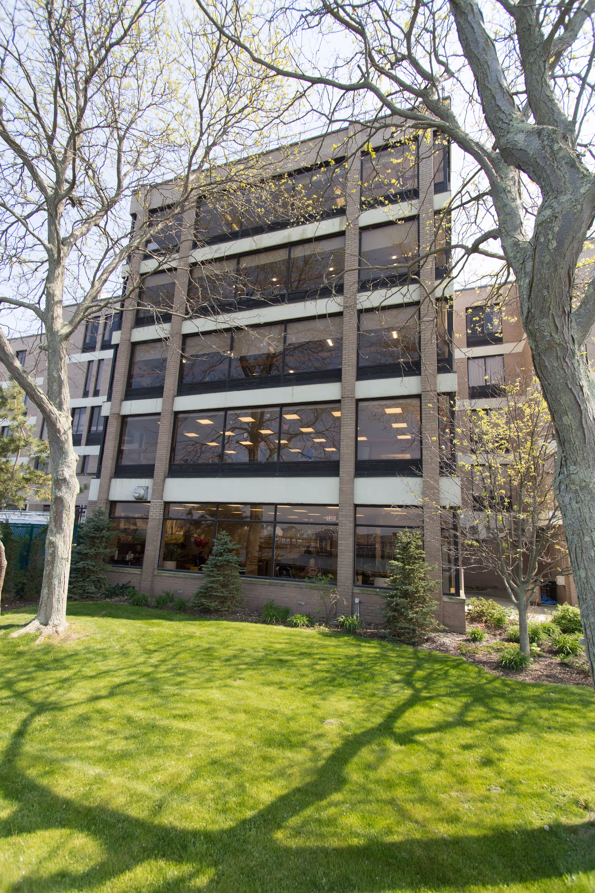 Front view of a multi-story nursing facility with large windows and trees.