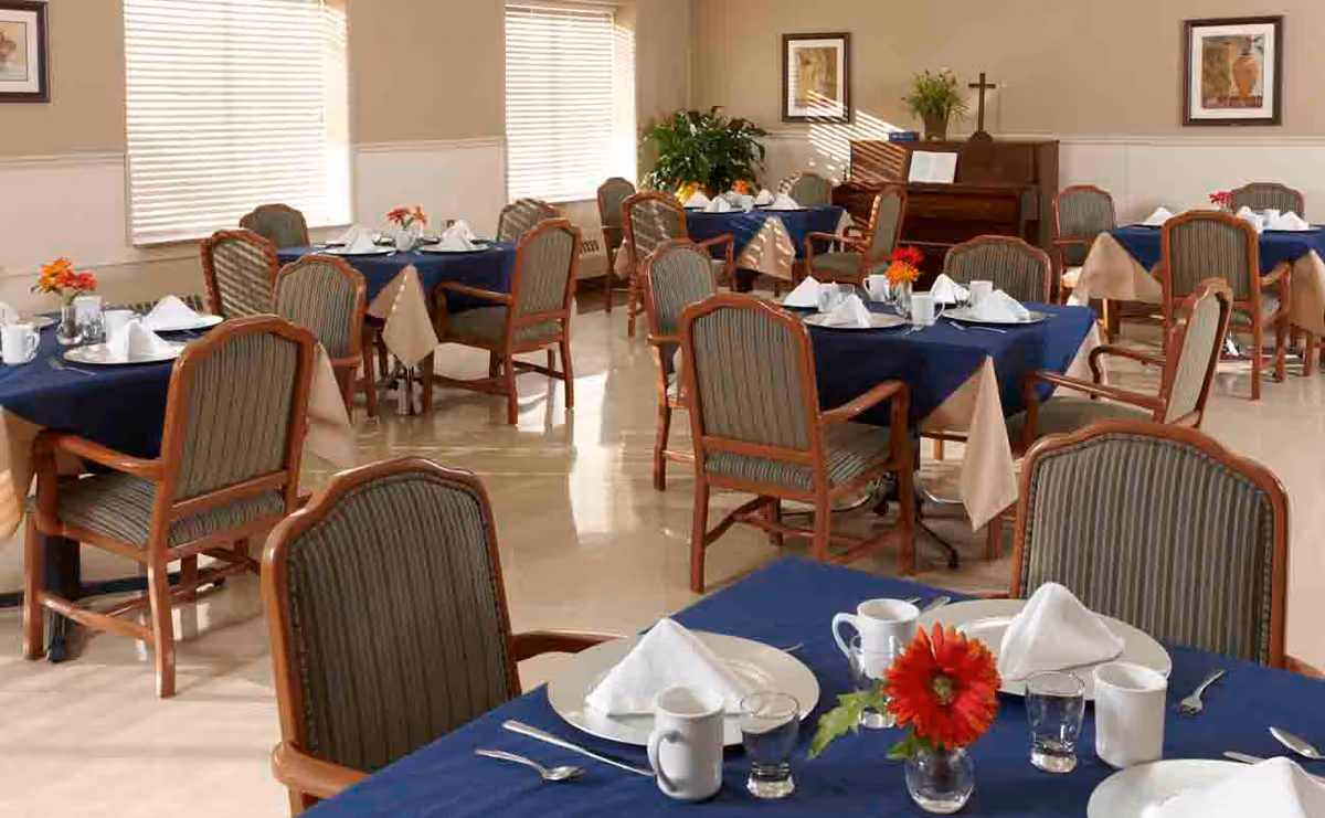 Spacious dining room with round tables covered in navy linens and chairs.