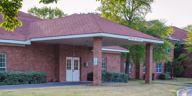 Brick building with a covered entrance labeled Parkway Heights, outdoor lawn in foreground.