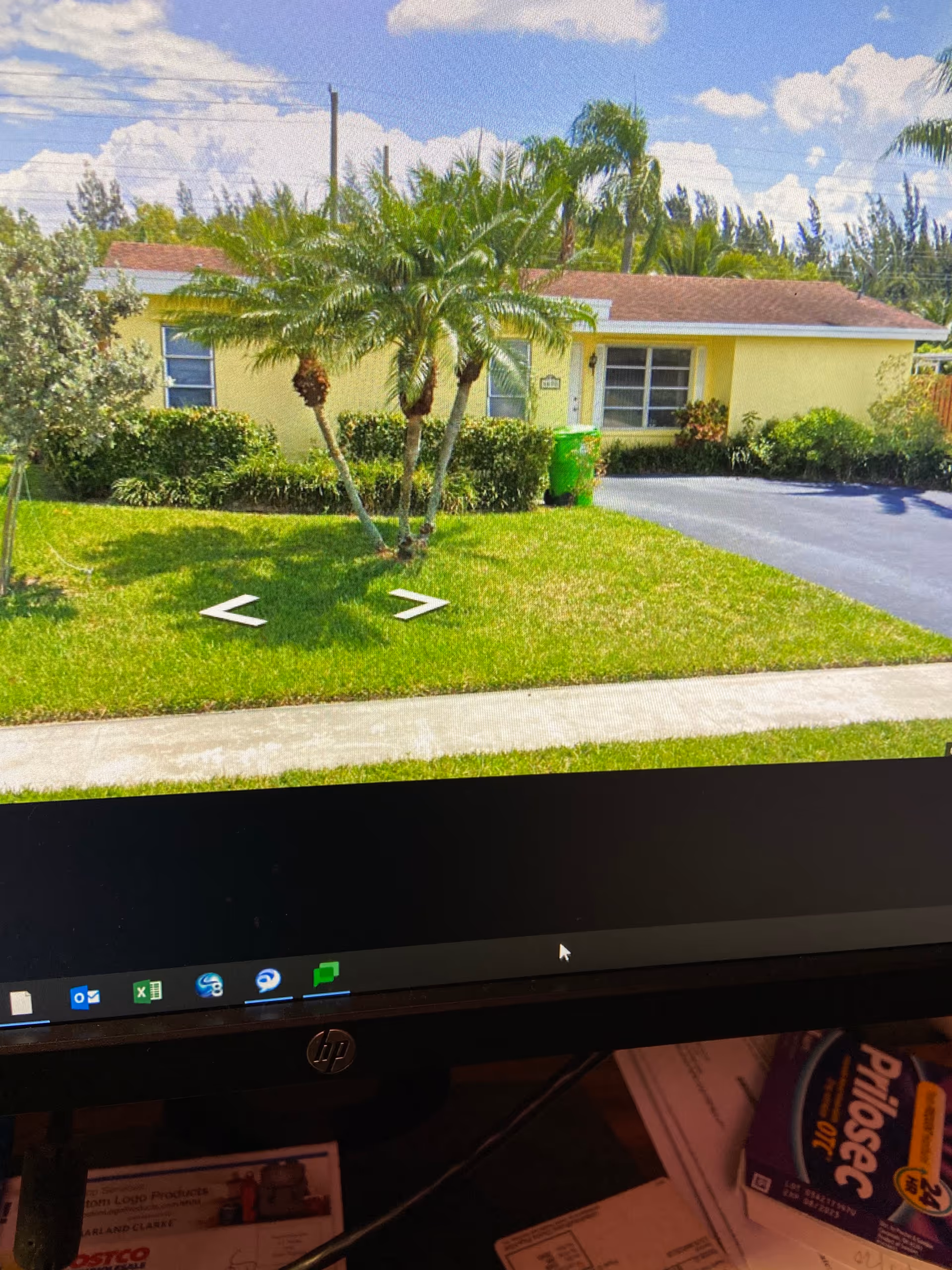 A single-story yellow senior living facility with palm trees and a driveway in front.