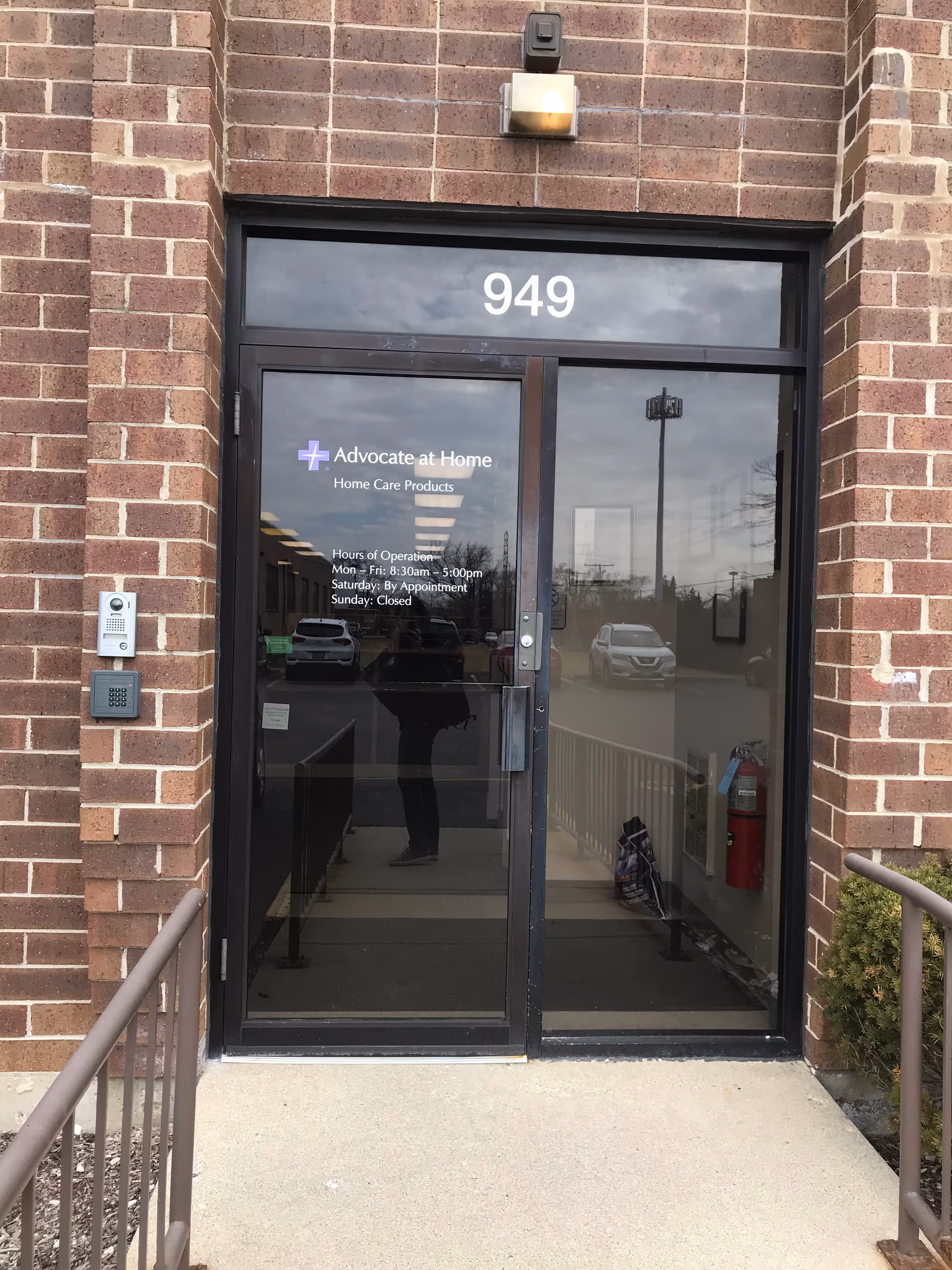 Brick building entrance with glass doors labeled Advocate at Home and the number 949.