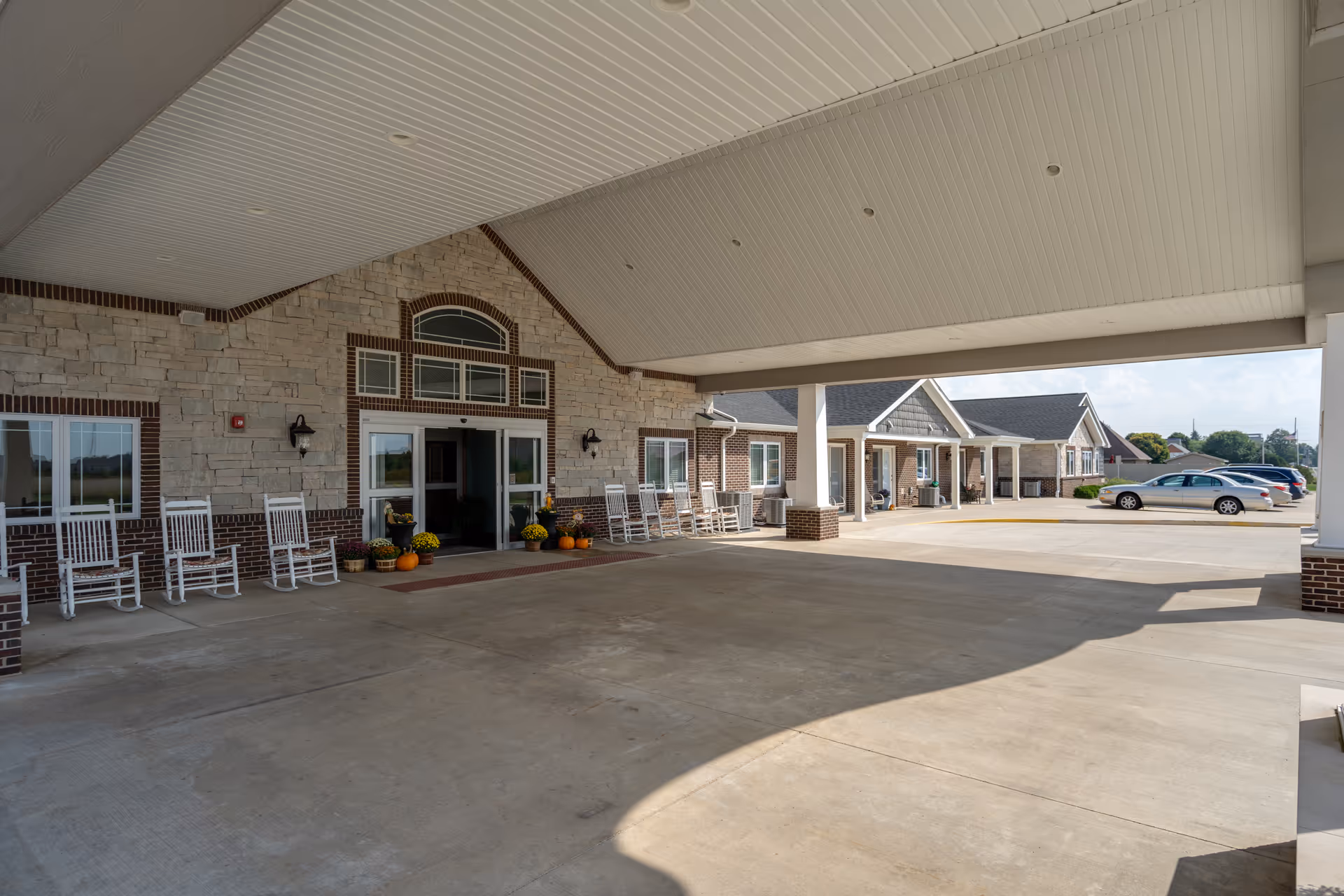Covered entrance and brick exterior of Gibson City Villas of Holly Brook with rocking chairs.