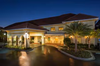 Nighttime exterior of The Windsor at Ortega with illuminated entrance and palm trees.