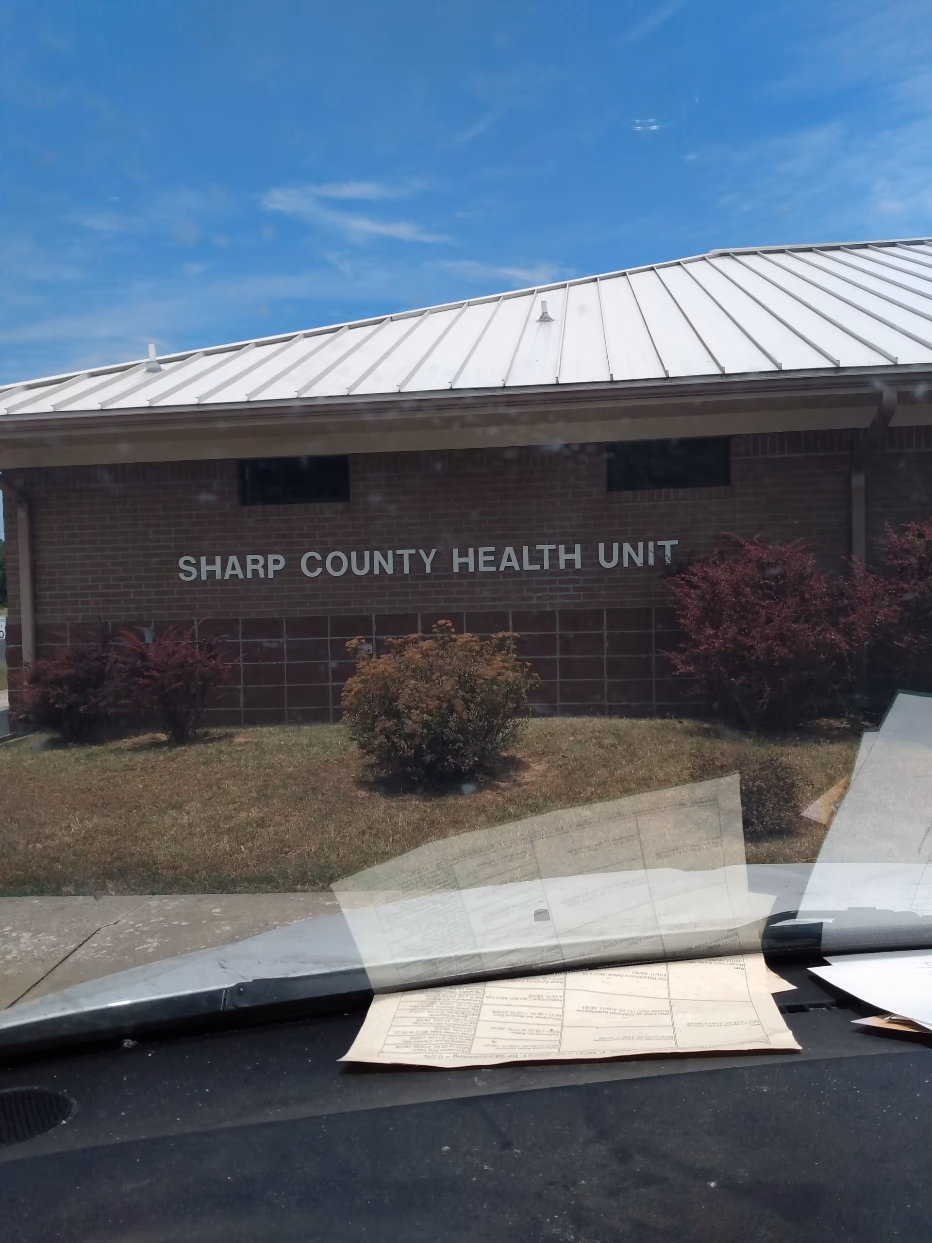 Exterior view of Sharp County Health Unit with brick facade and shrubs in front.