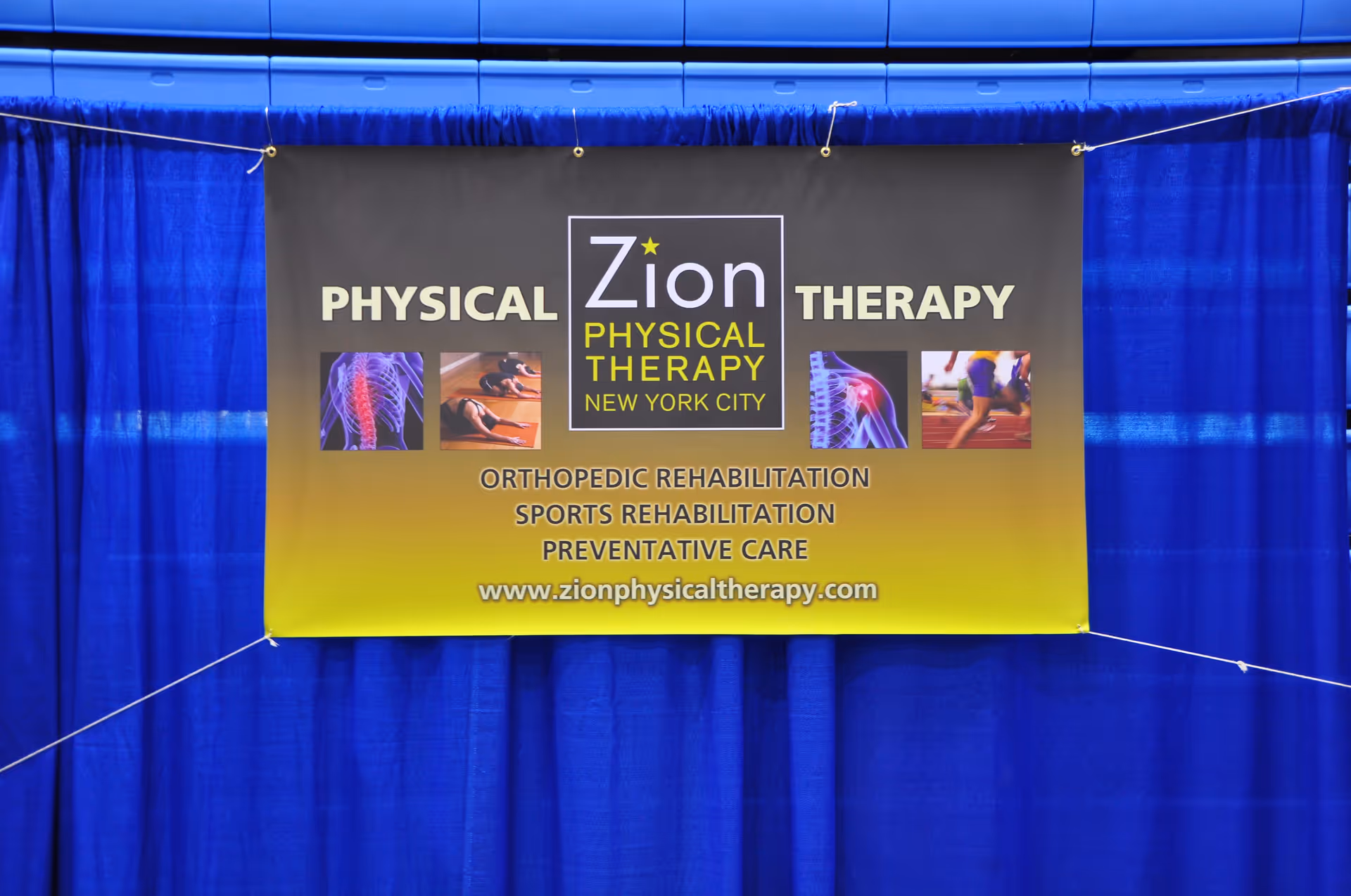 Indoor view of a Zion Physical Therapy banner hanging against blue curtains.