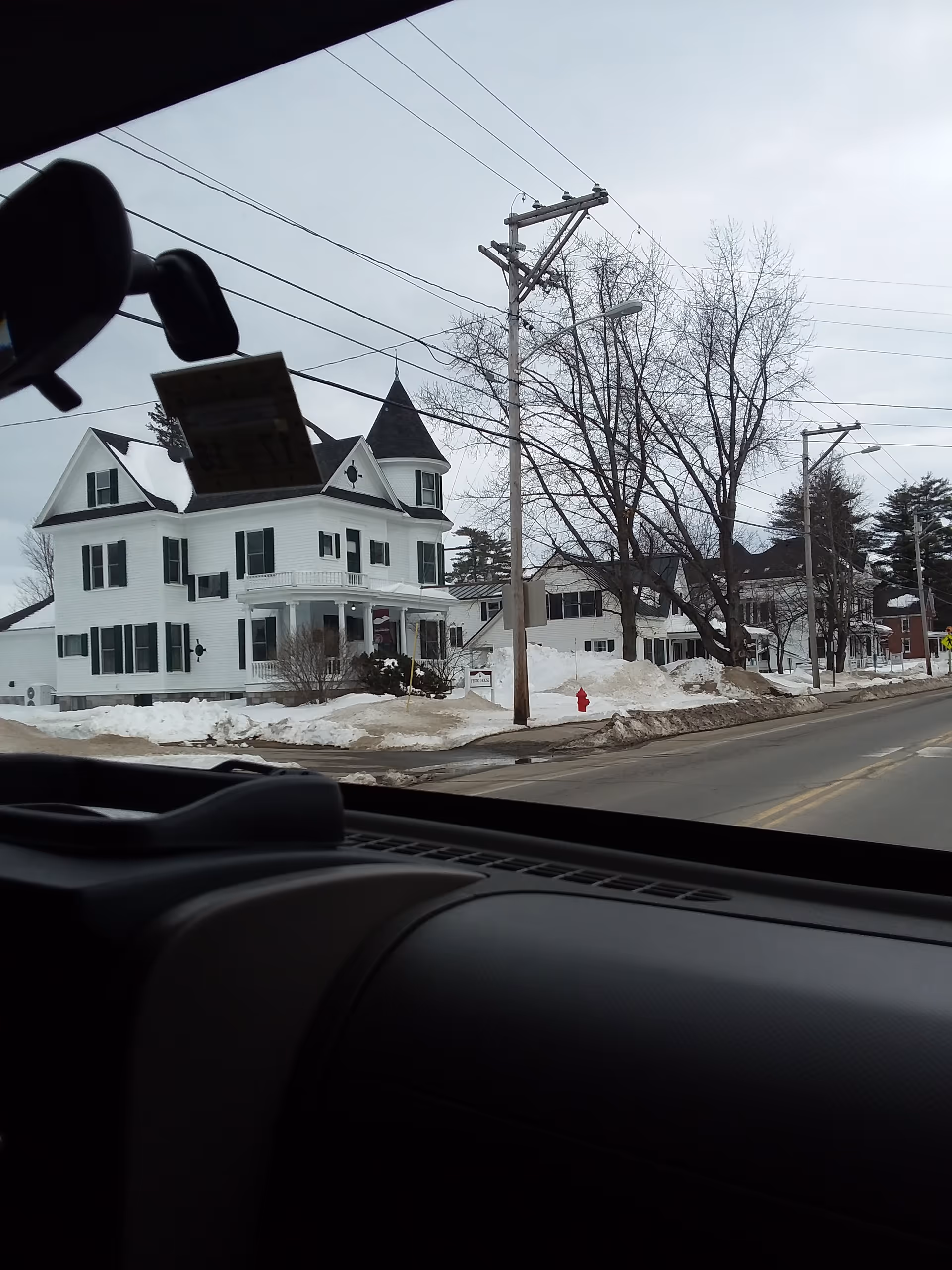 Snowy street view of a white Victorian-style building with turret, identified as Pierce House.