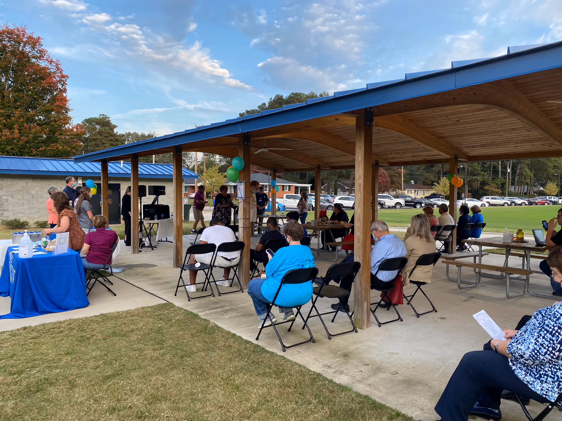 Outdoor pavilion at Hospice of Wilson with attendees seated, balloons, and a table setup.