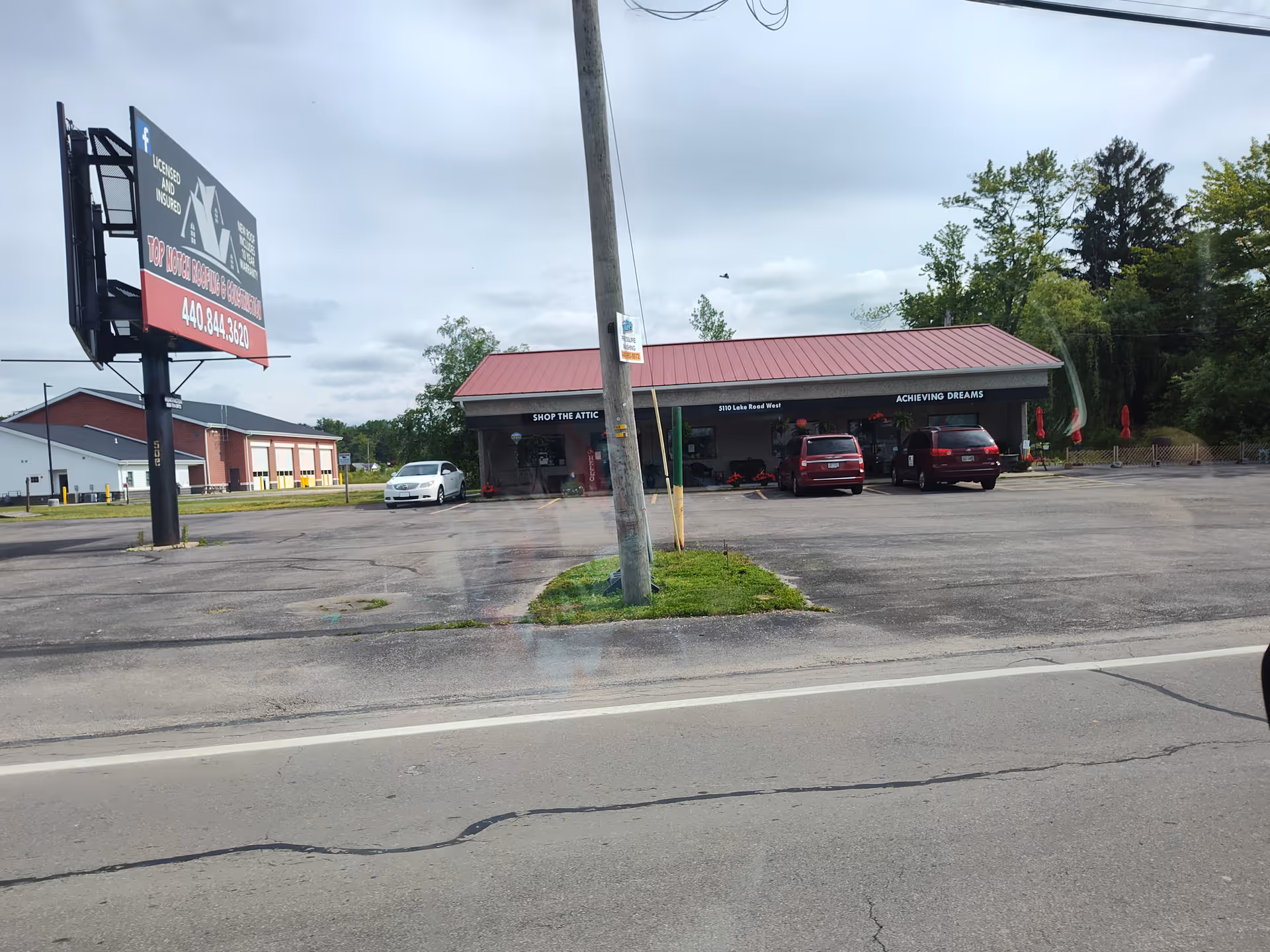 Front view of a single-story storefront labeled Achieving Dreams with parked cars.