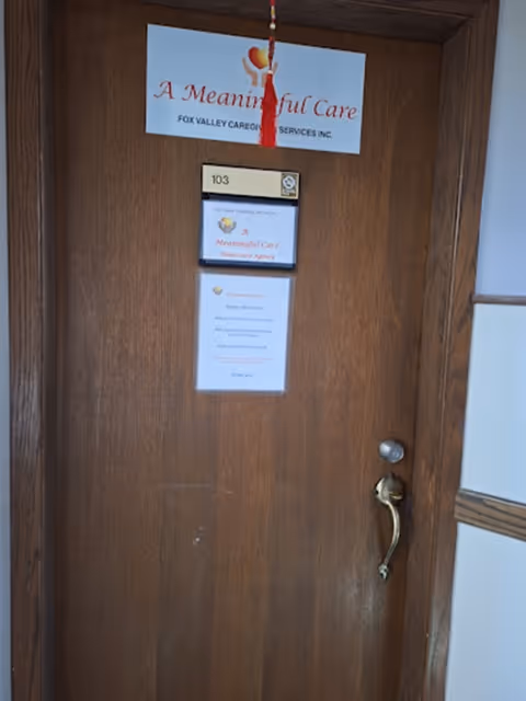 Wooden interior door with a 'A Meaningful Care' sign and room number 103.